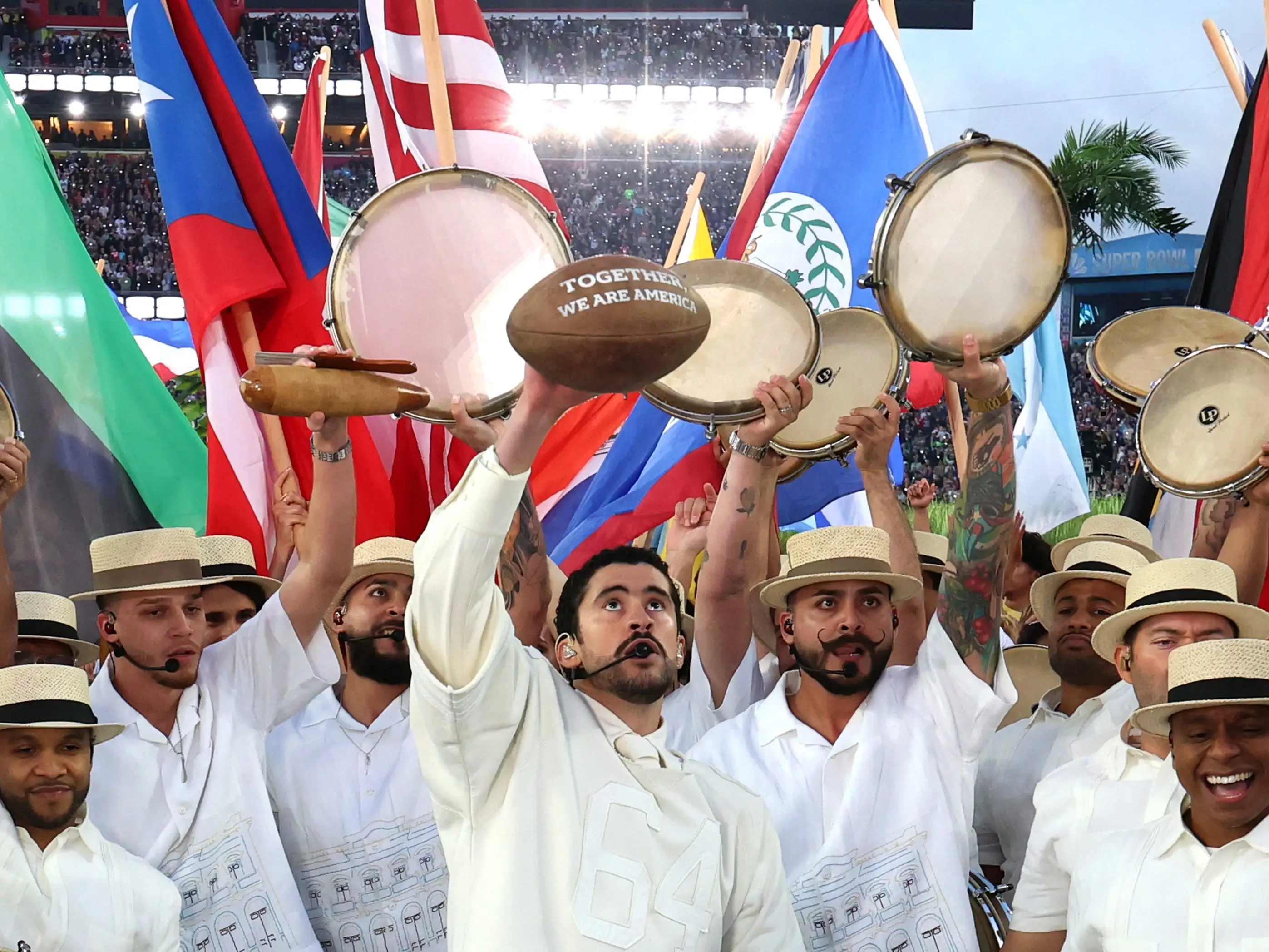 Bad Bunny holds up a football with the words 