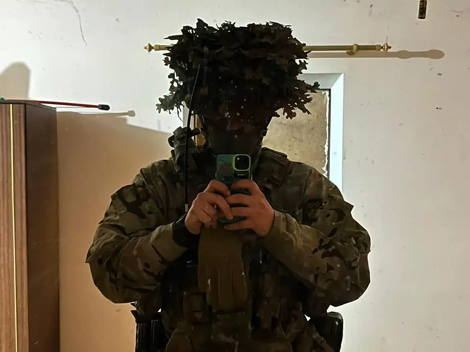 Nefor takes a mirror selfie with military fatigues and camouflage.