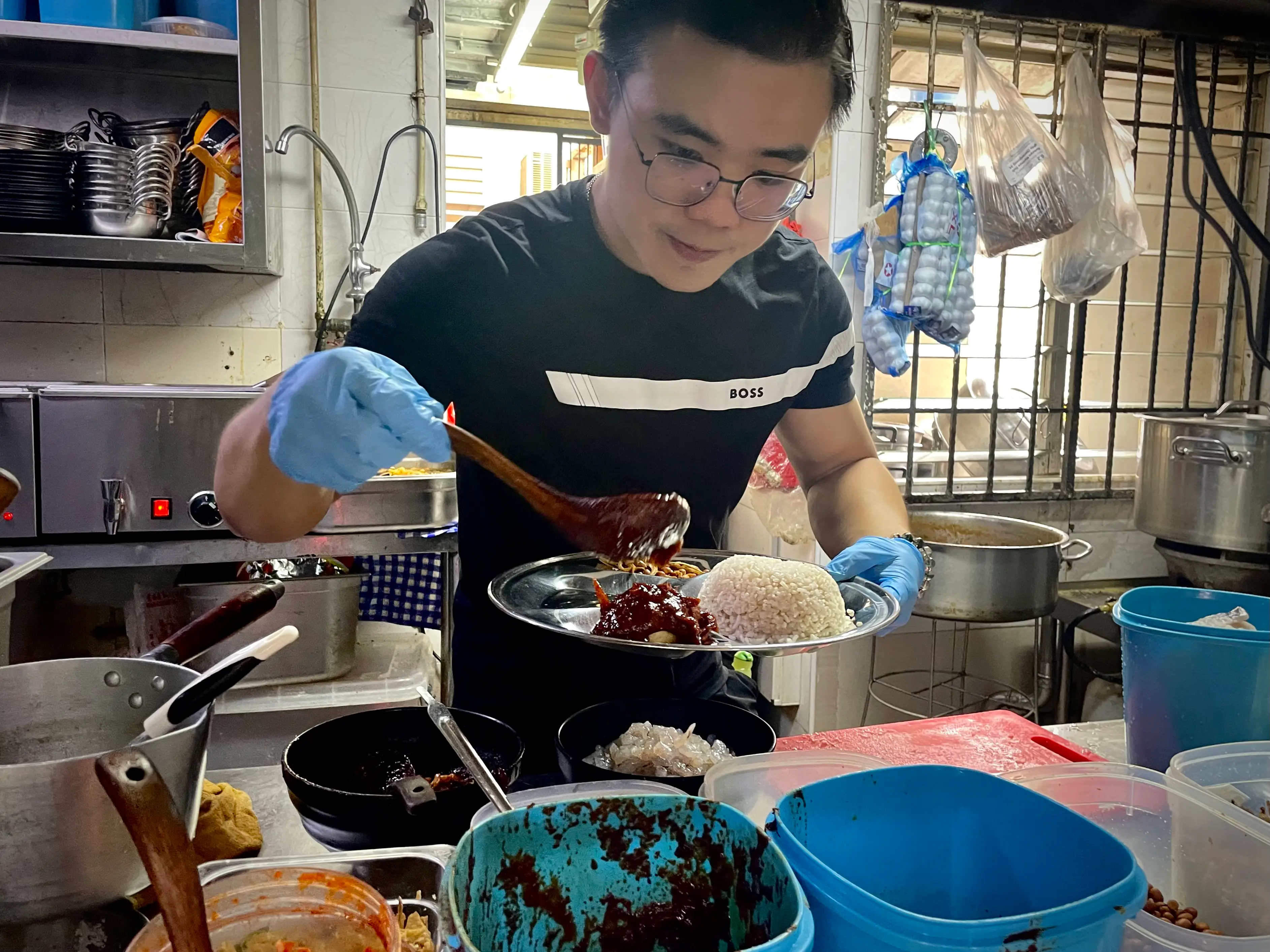 Ernest Ang, 24, is plating a dish in his restaurant.