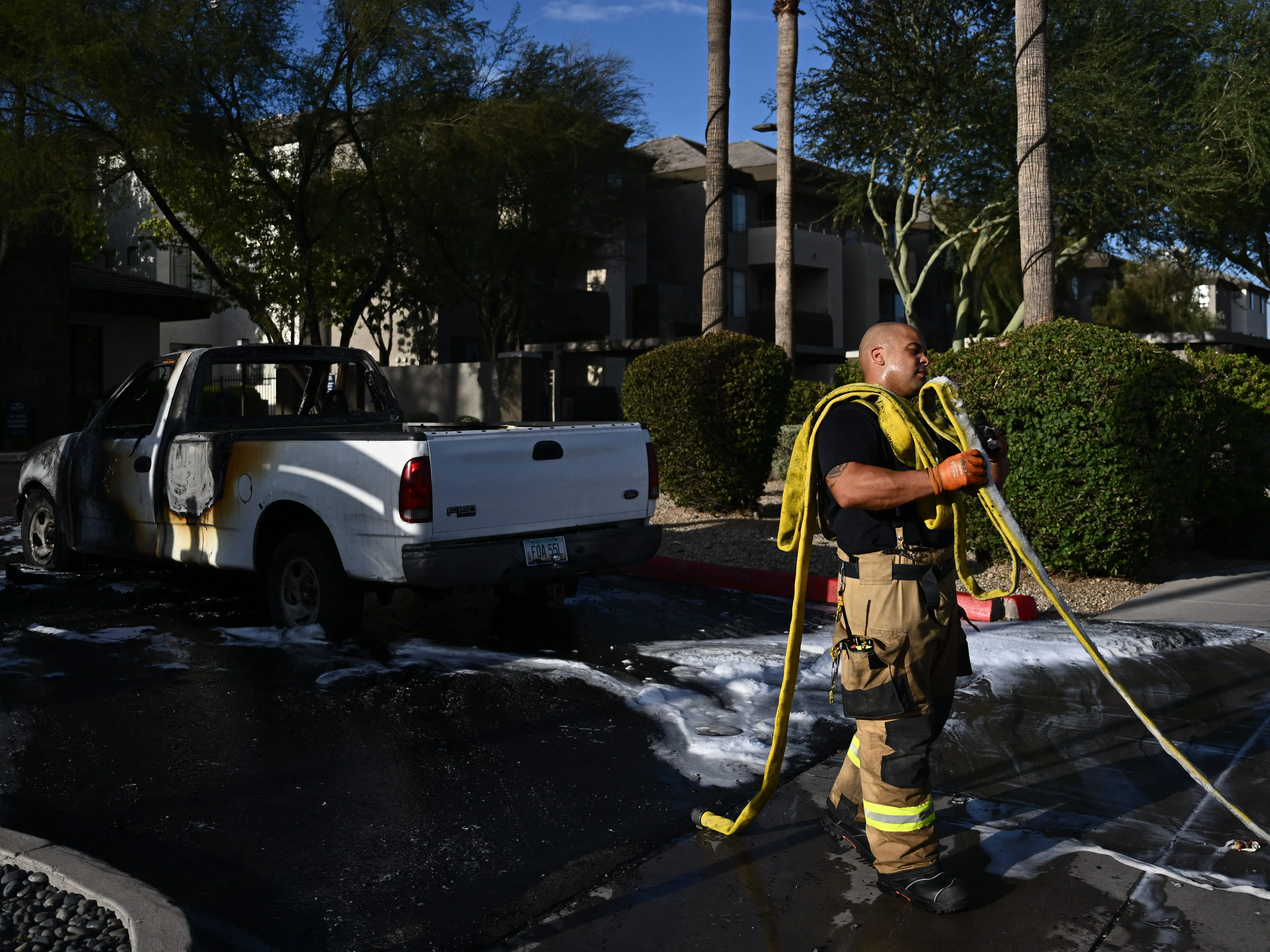A firefighter carrying a hose after putting out a car fire during a heatwave in Phoenix, Arizona.