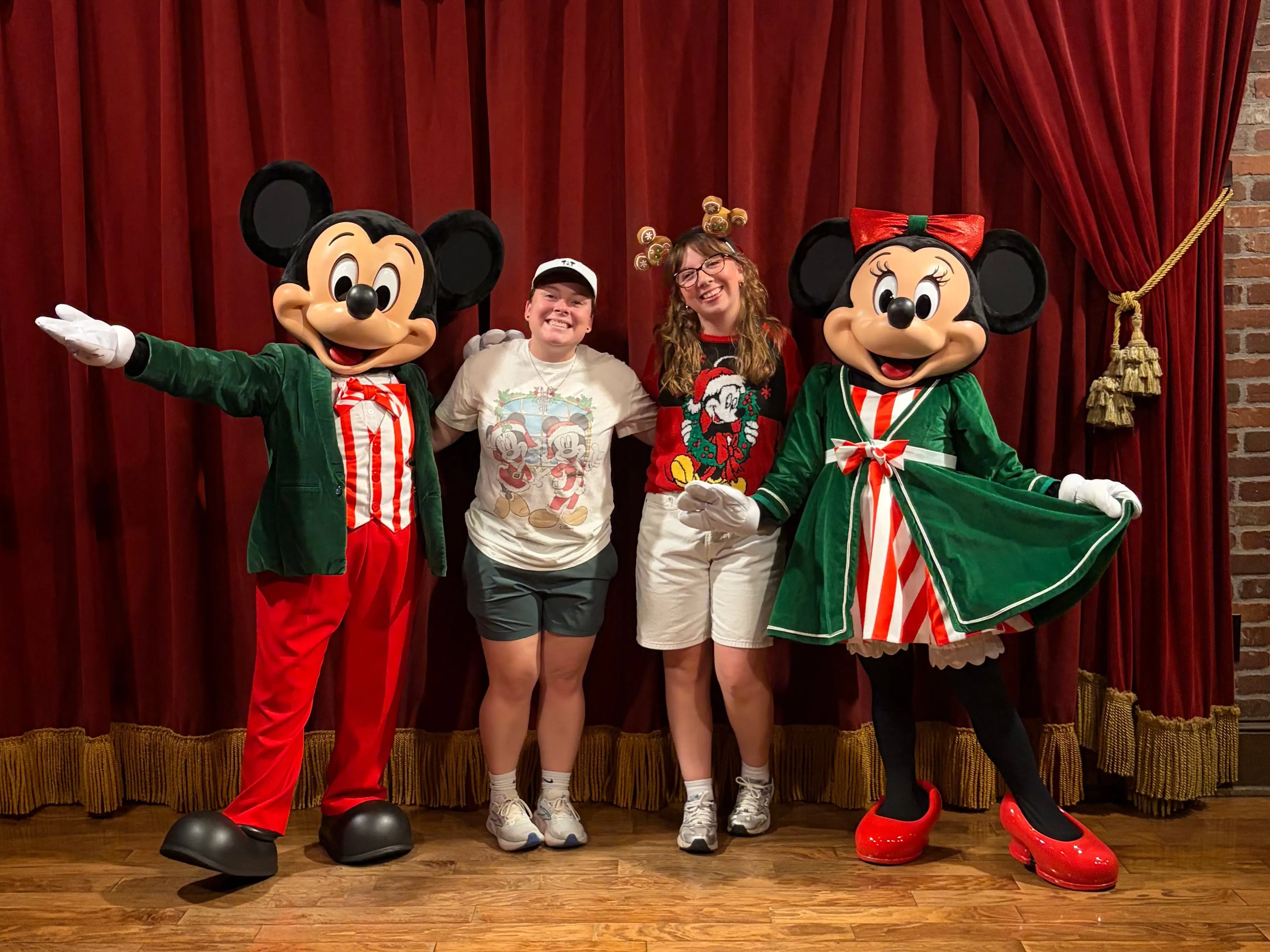 Author and their partner smiling with Mickey and Minnie in festive outfits