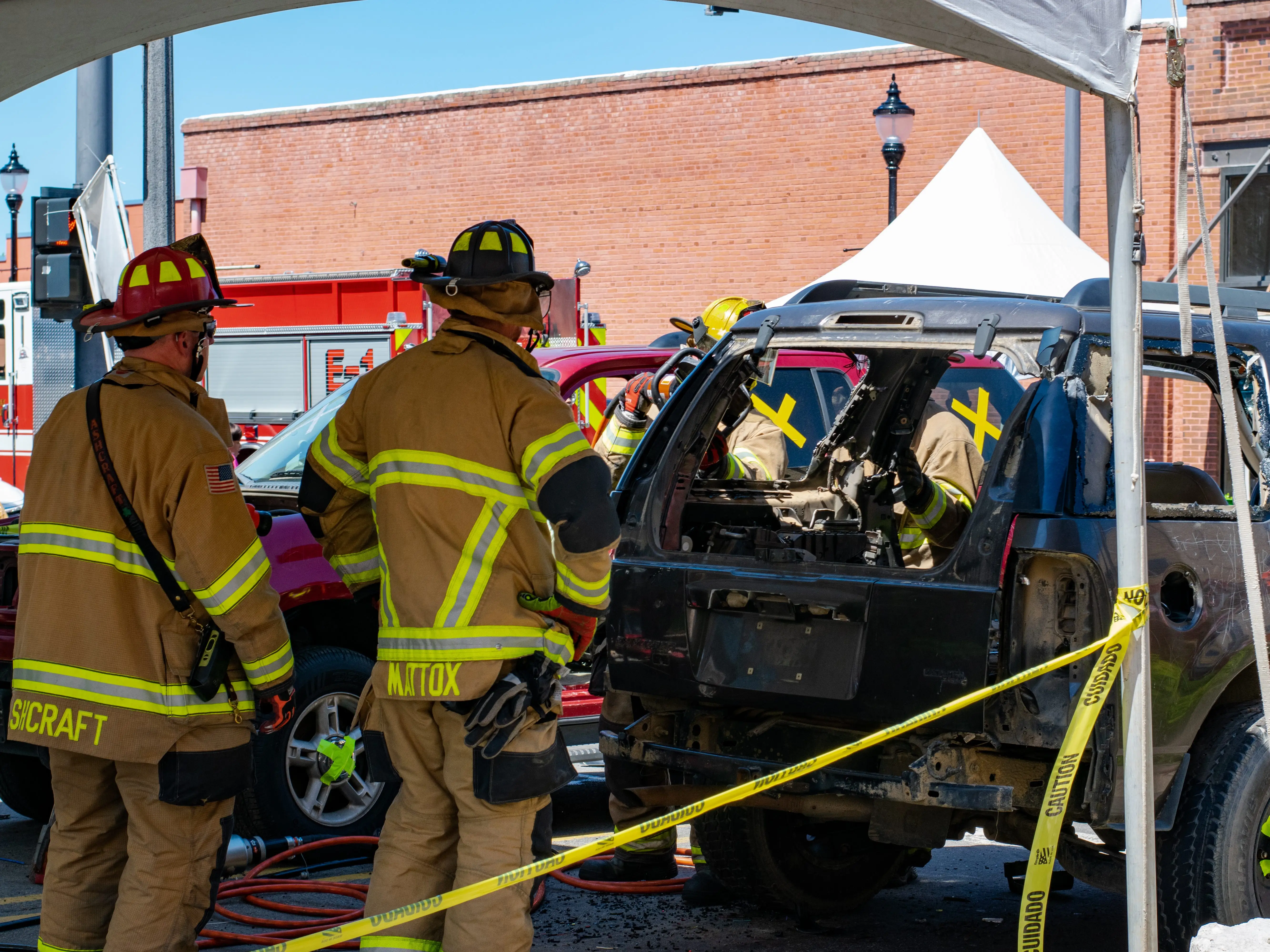 Two firefighters in front of a car demonstrating a 