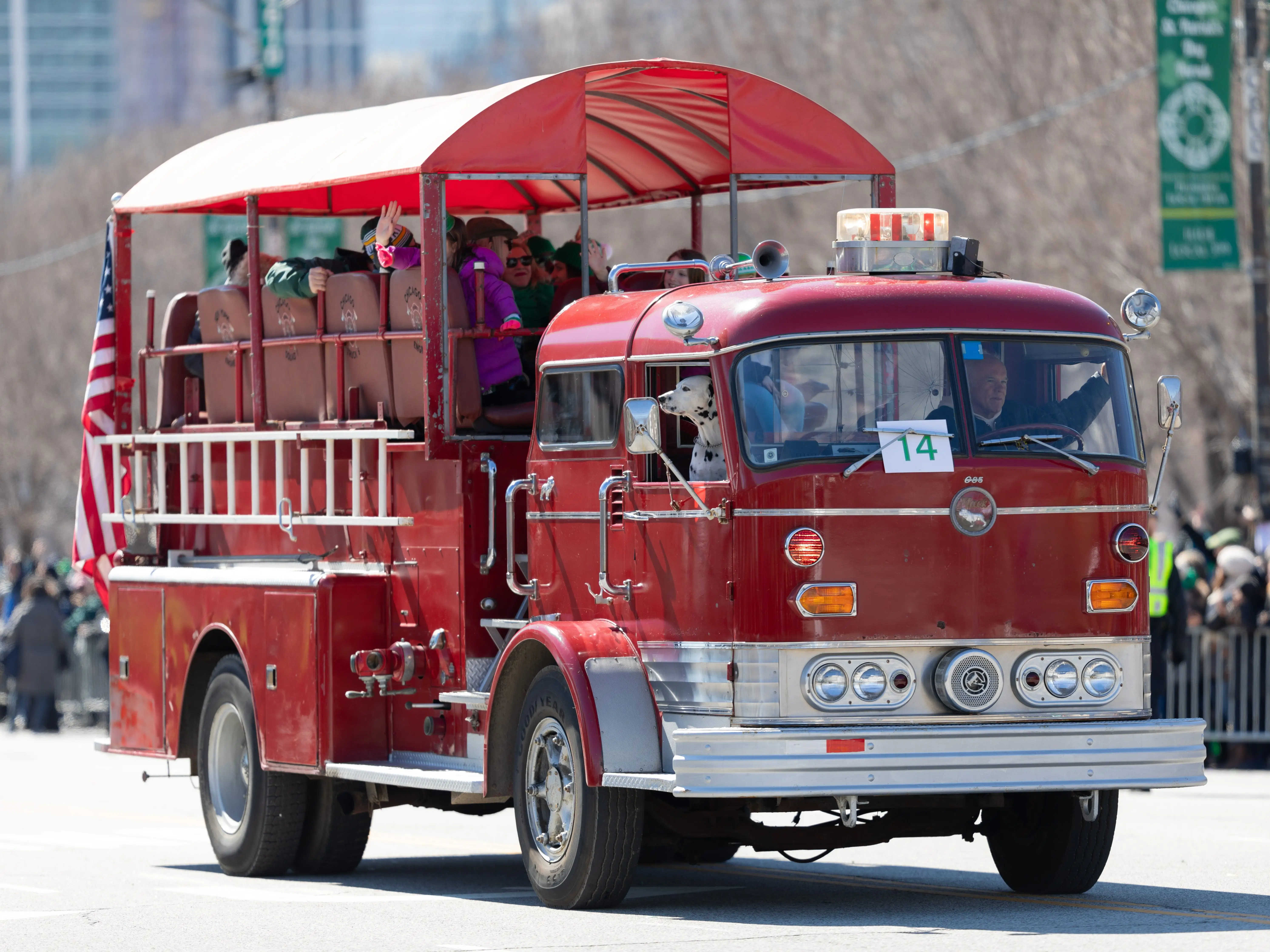An old-fashioned firetruck transports attendees at a St. Patrick's Day parade in Chicago, Illinois.
