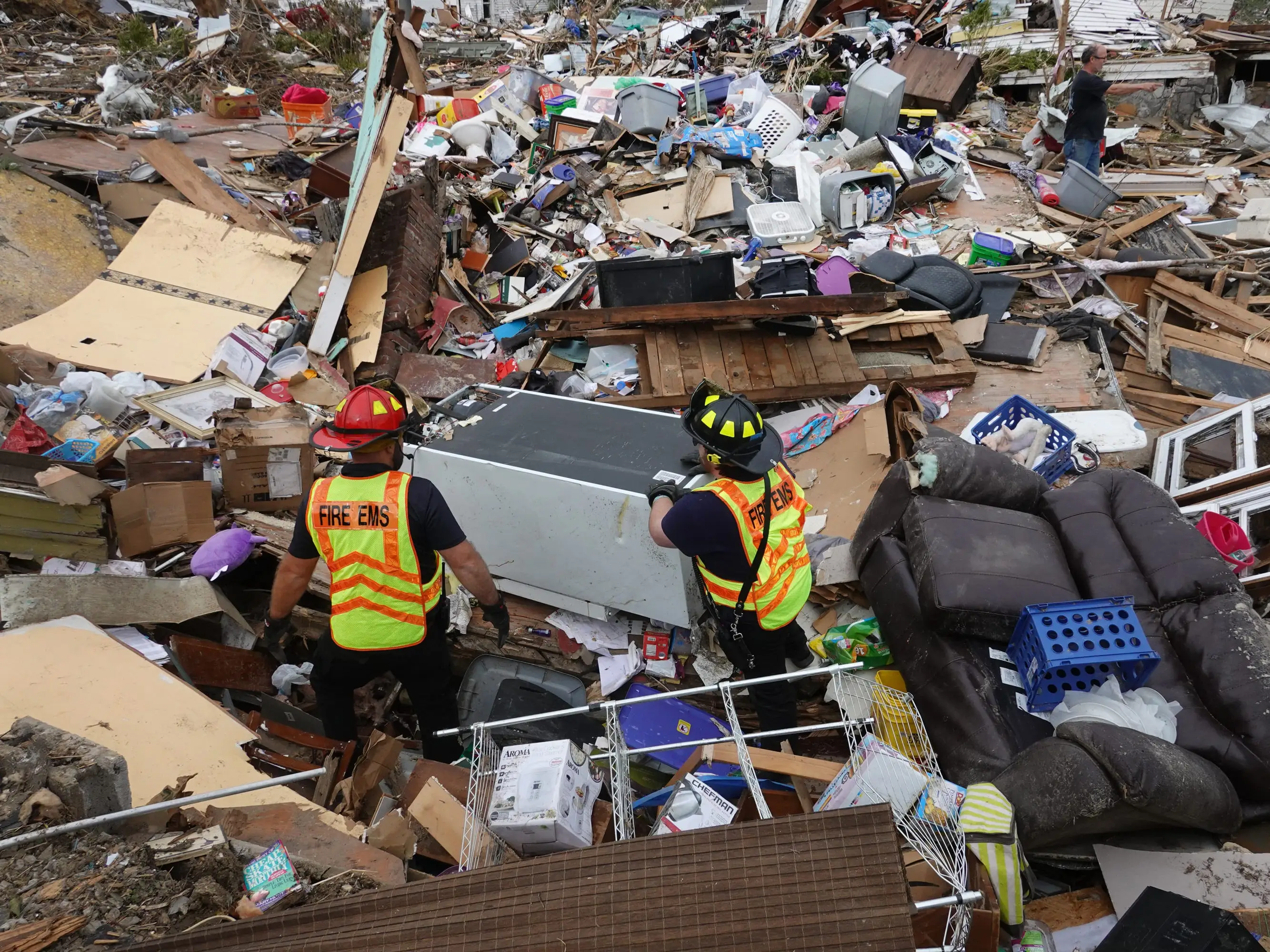 Two firefighters standing amidst a pile of rubble after a tornado in Dawson Springs, Kentucky.
