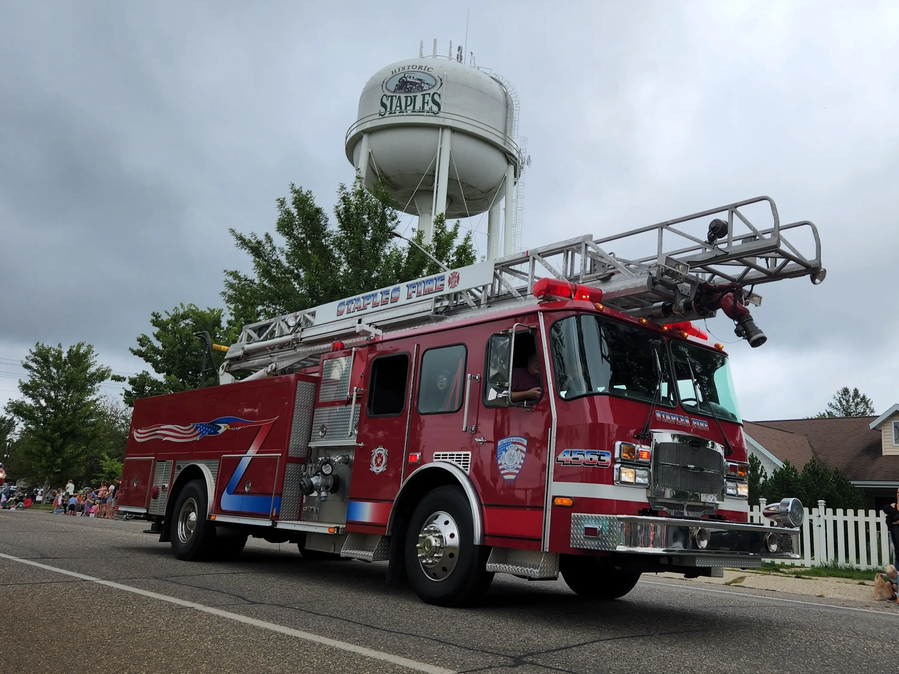 A firetruck drives with a water tower in the background in a parade in Staples, Minnesota.