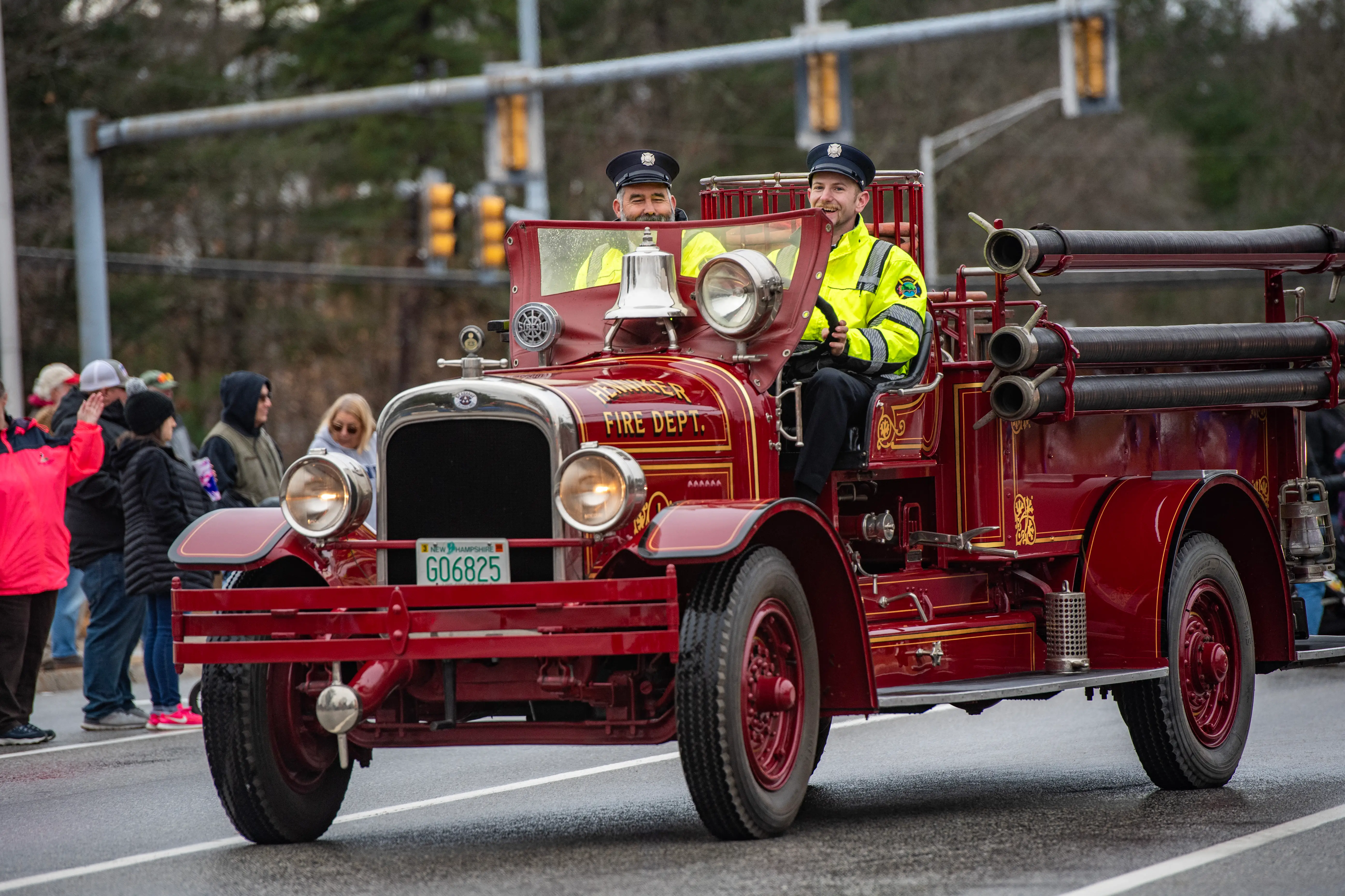 Firefighters driving a vintage firetruck at a Christmas parade in Concord, New Hampshire.