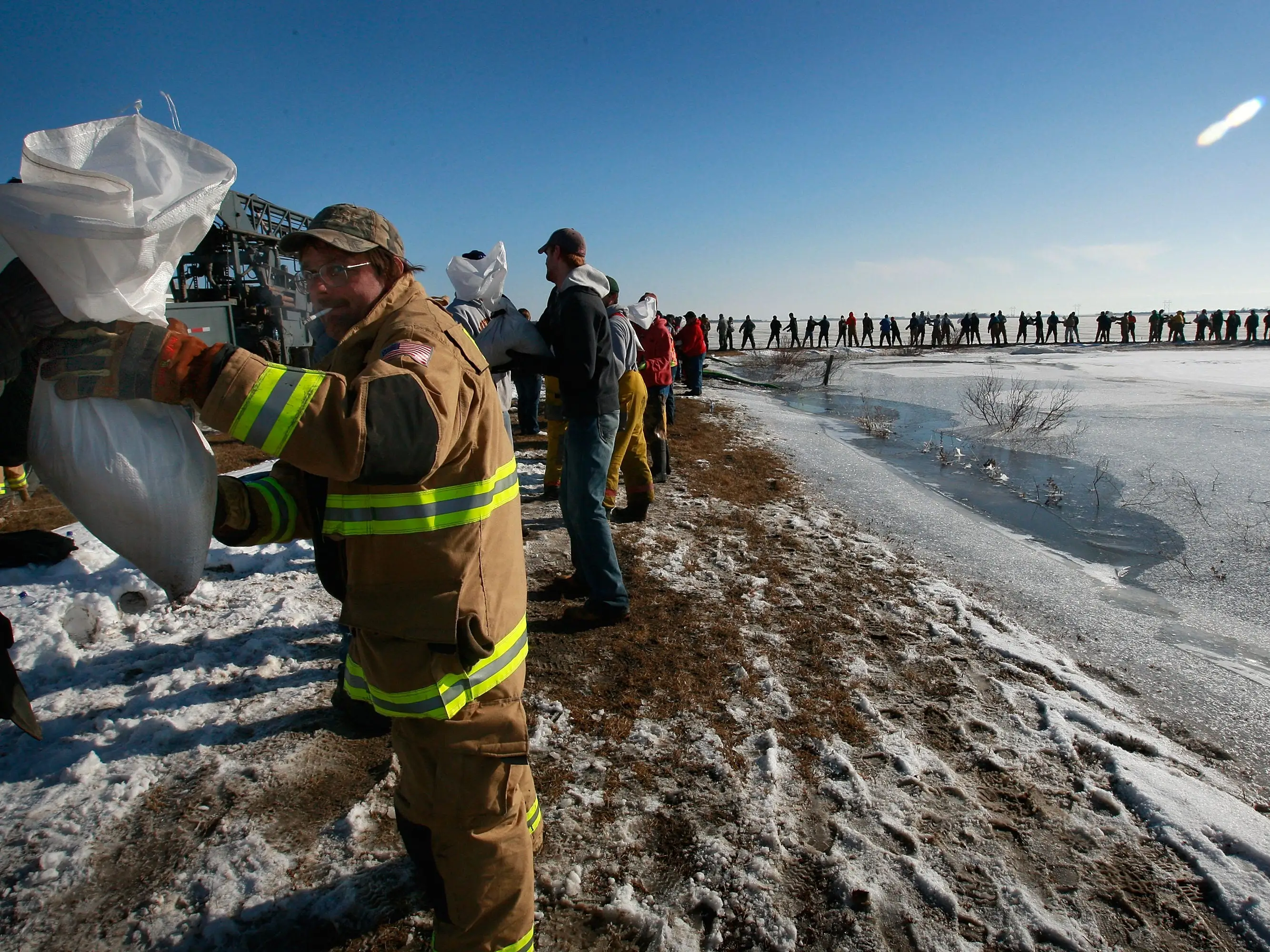 A firefighter holds a bag on a line of volunteers to prepare for a flood in Horace, North Dakota.