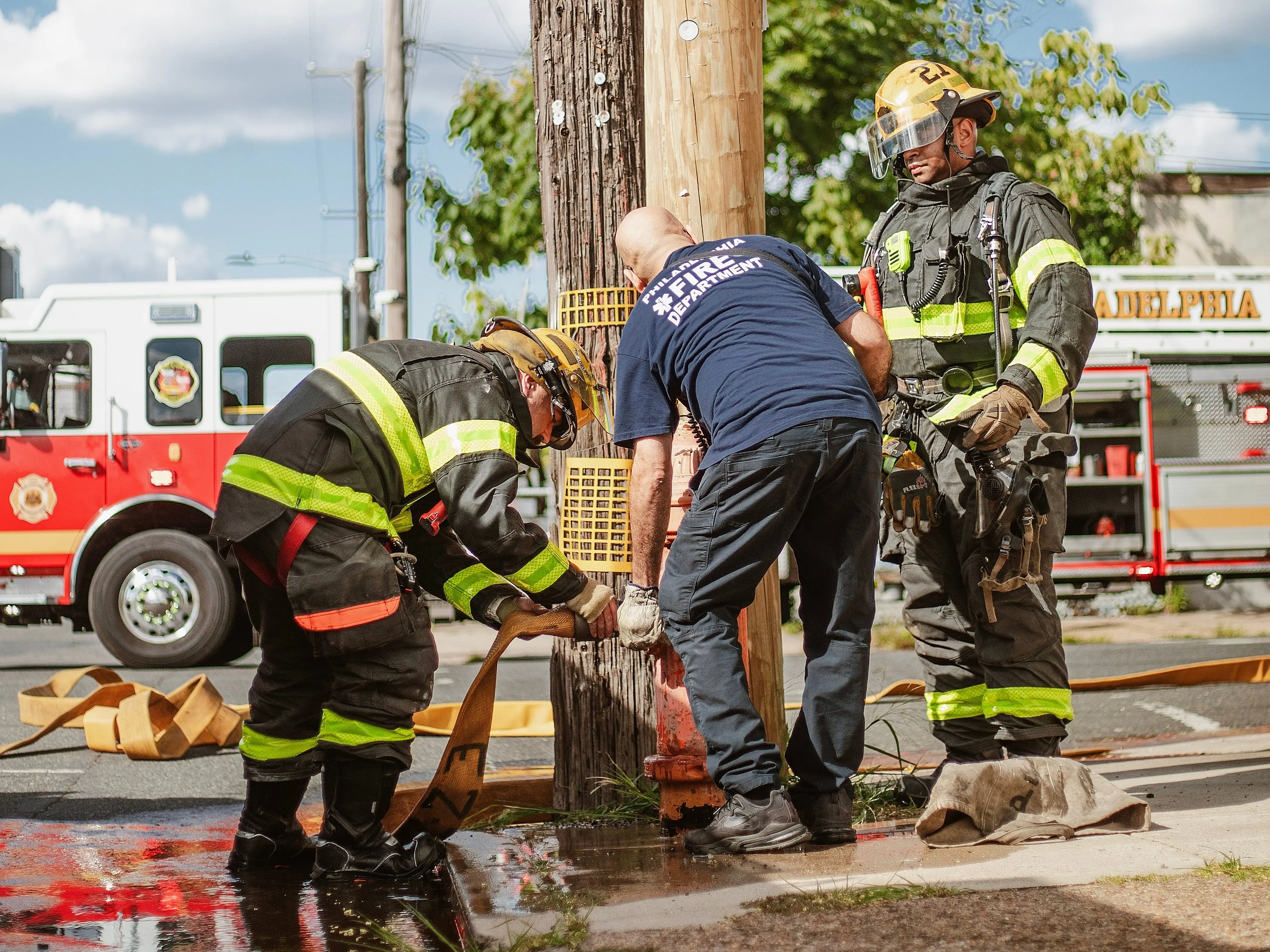 Three firefighters fill a hydrant at an intersection in Philadelphia, Pennsylvania.