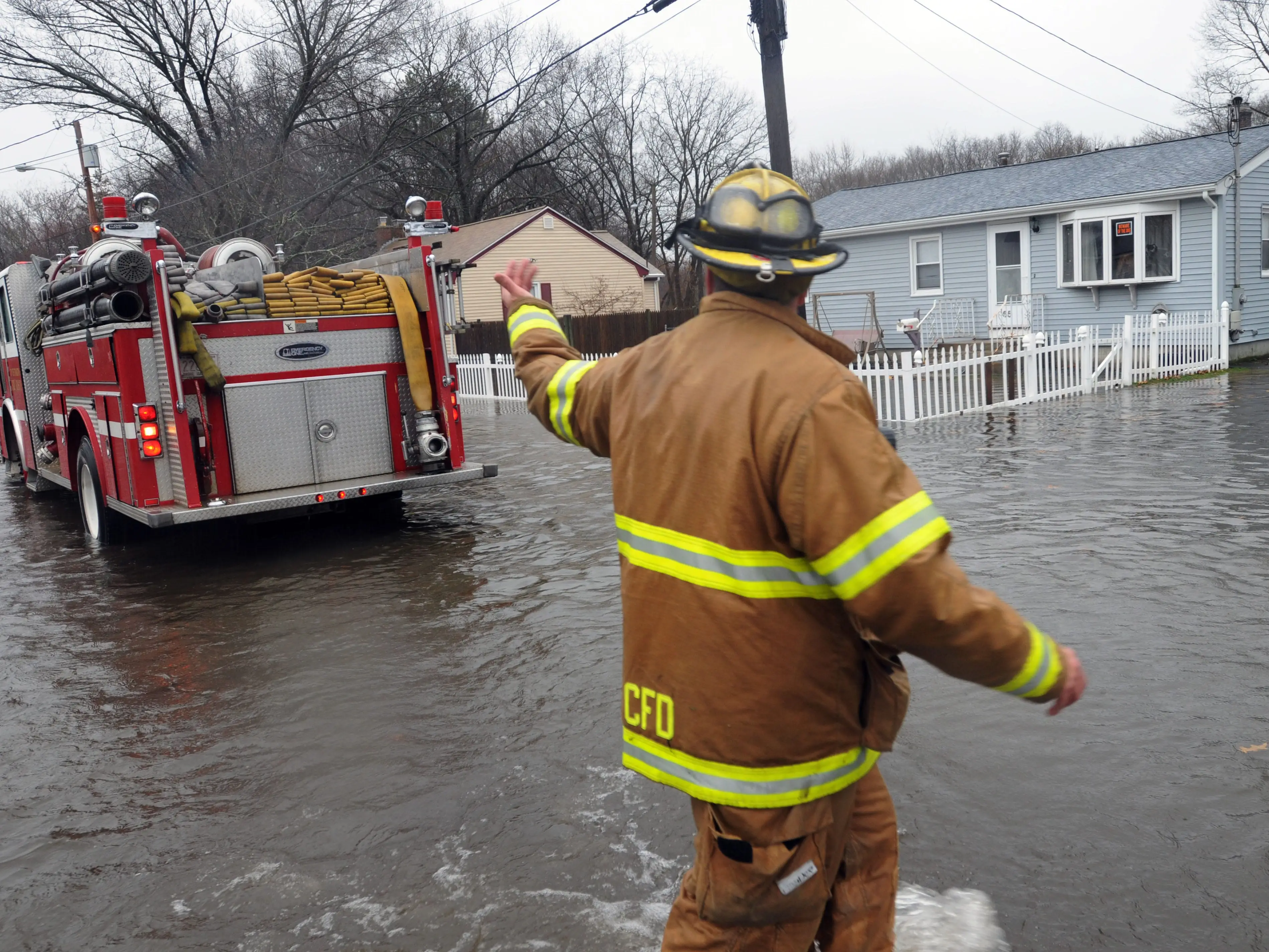 A firefighter directs a firetruck while standing in a flooded street in Cranston, Rhode Island.