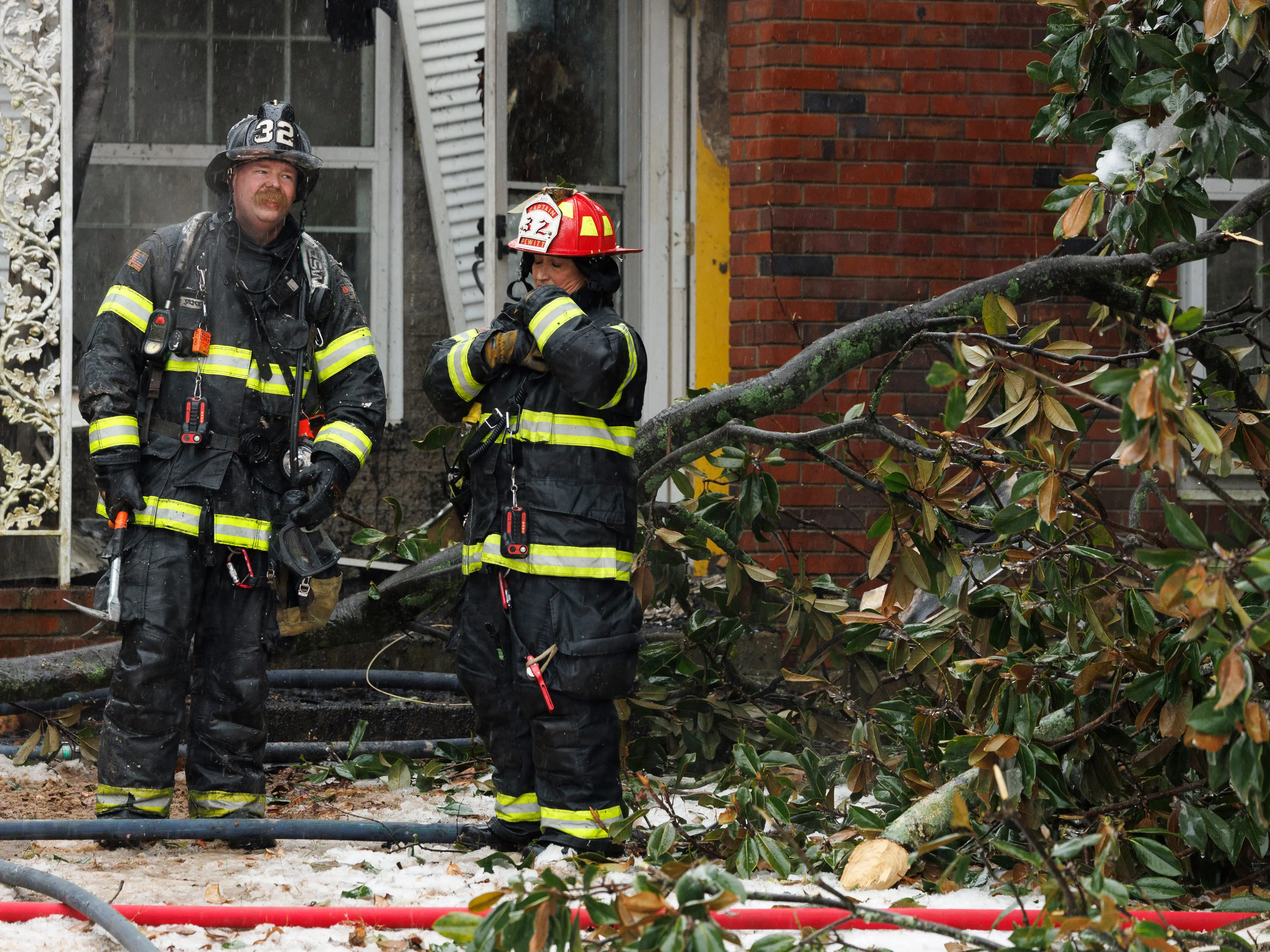 Firefighters standing next to a fallen branch after a house fire in Nashville, Tennessee.