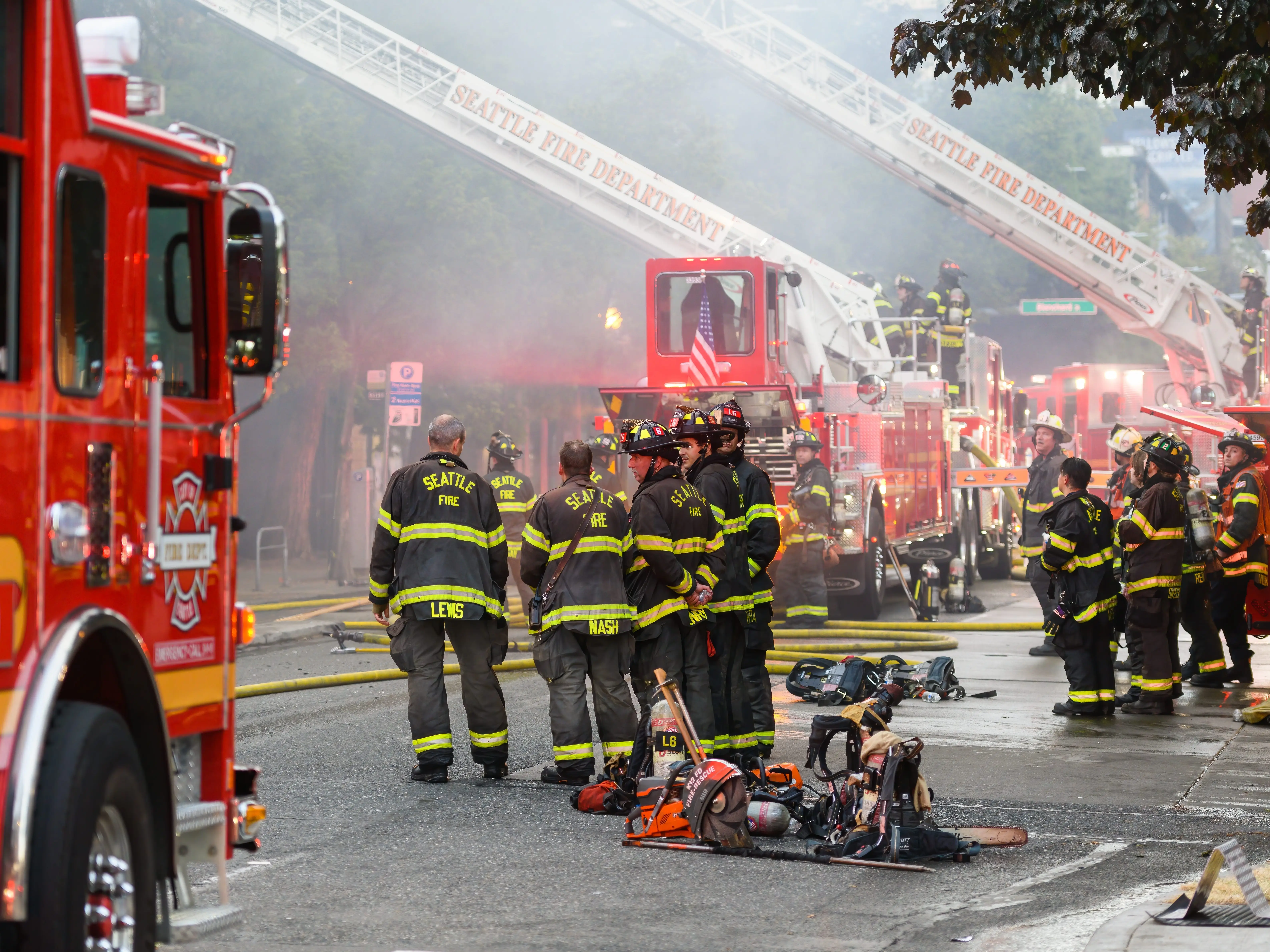 Firefighters gather in a huddle next to fire engines in response to a fire in Seattle, Washington.