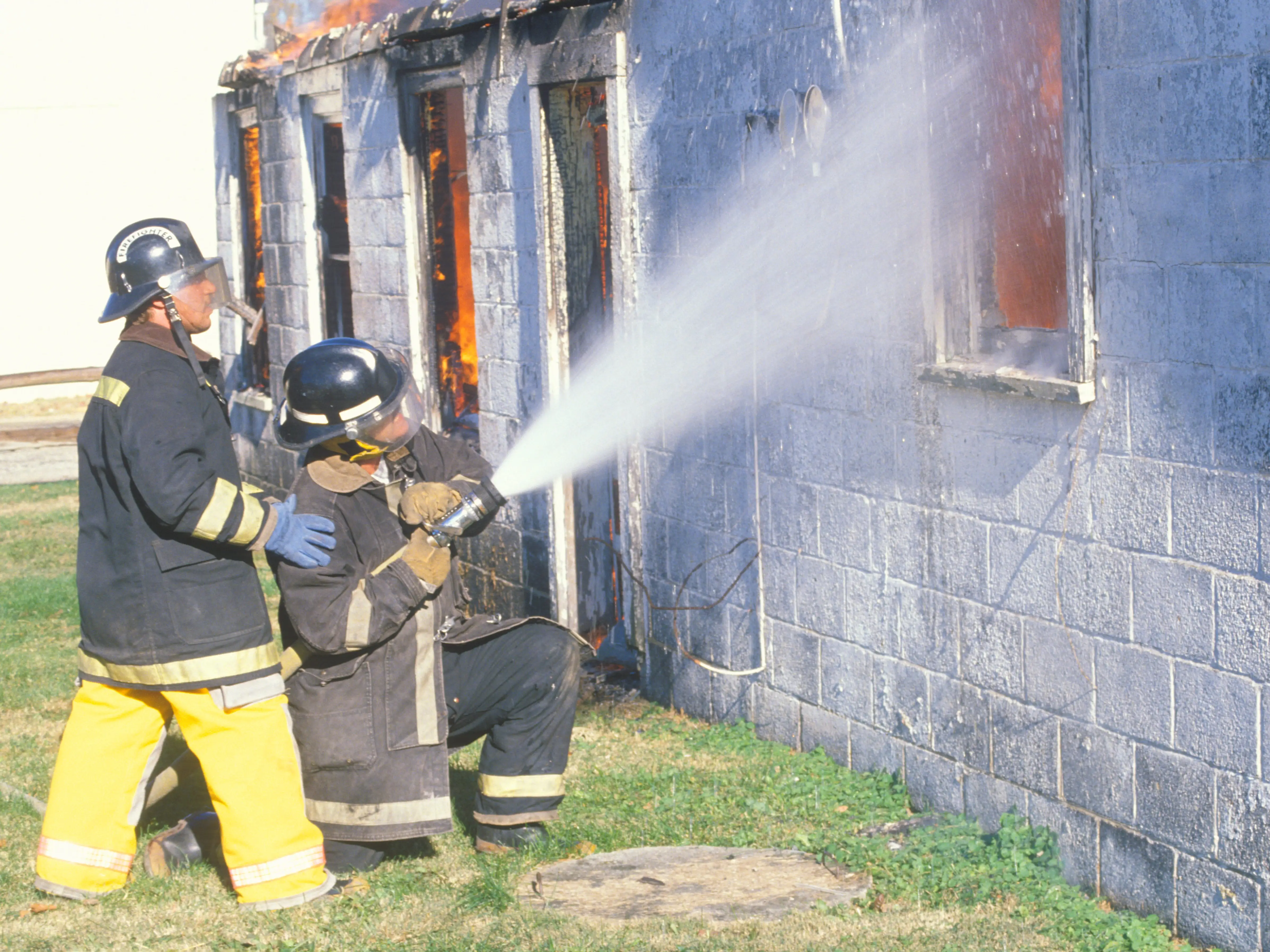 Two firefighters spray water at a house fire in West Virginia.