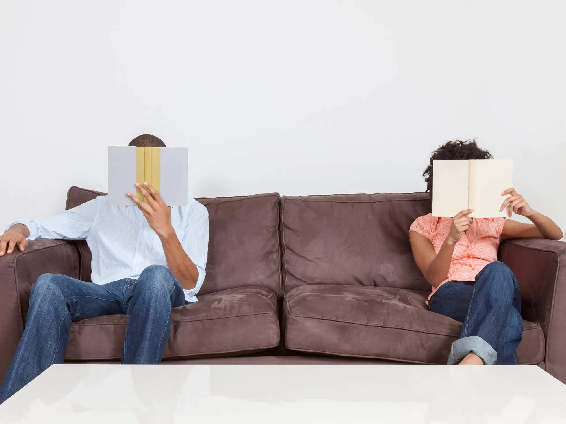 Couple reading books on couch separately.