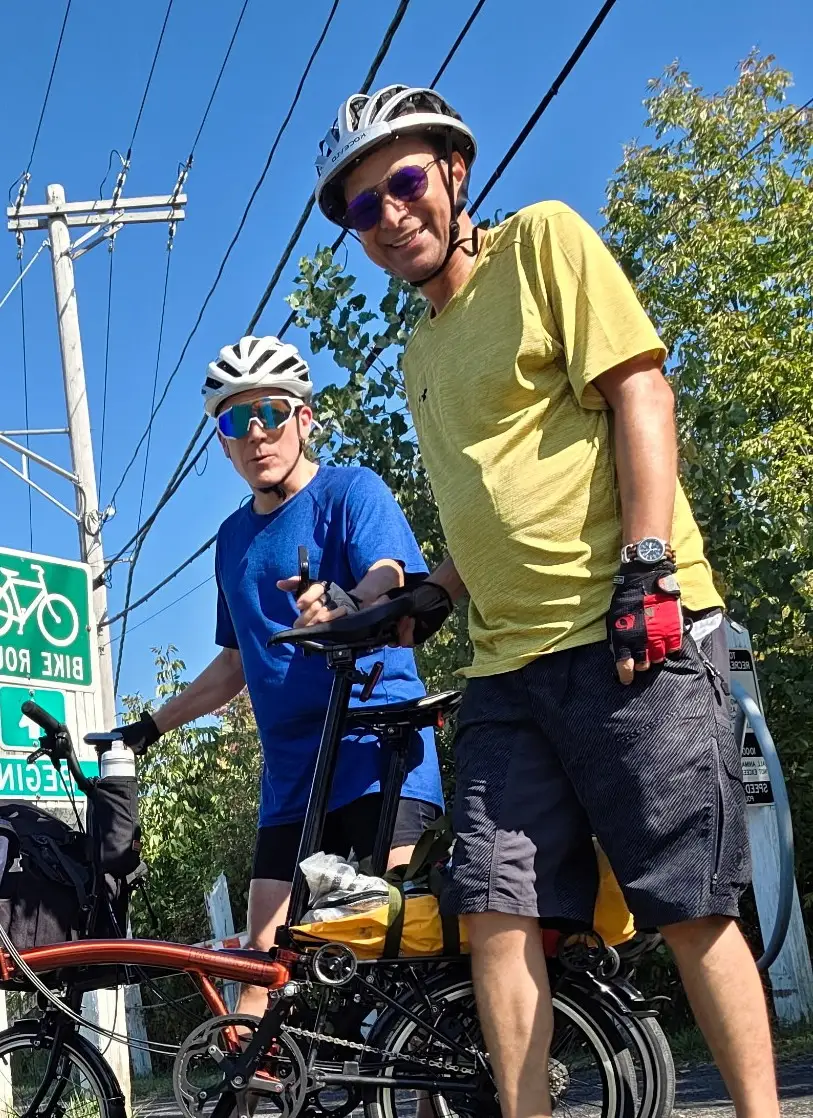 Scovel and his friend Bruno are holding bikes and wearing bike helmets.