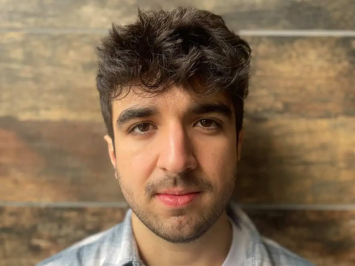 Kiva Lucero stands in front of a wooden wall.