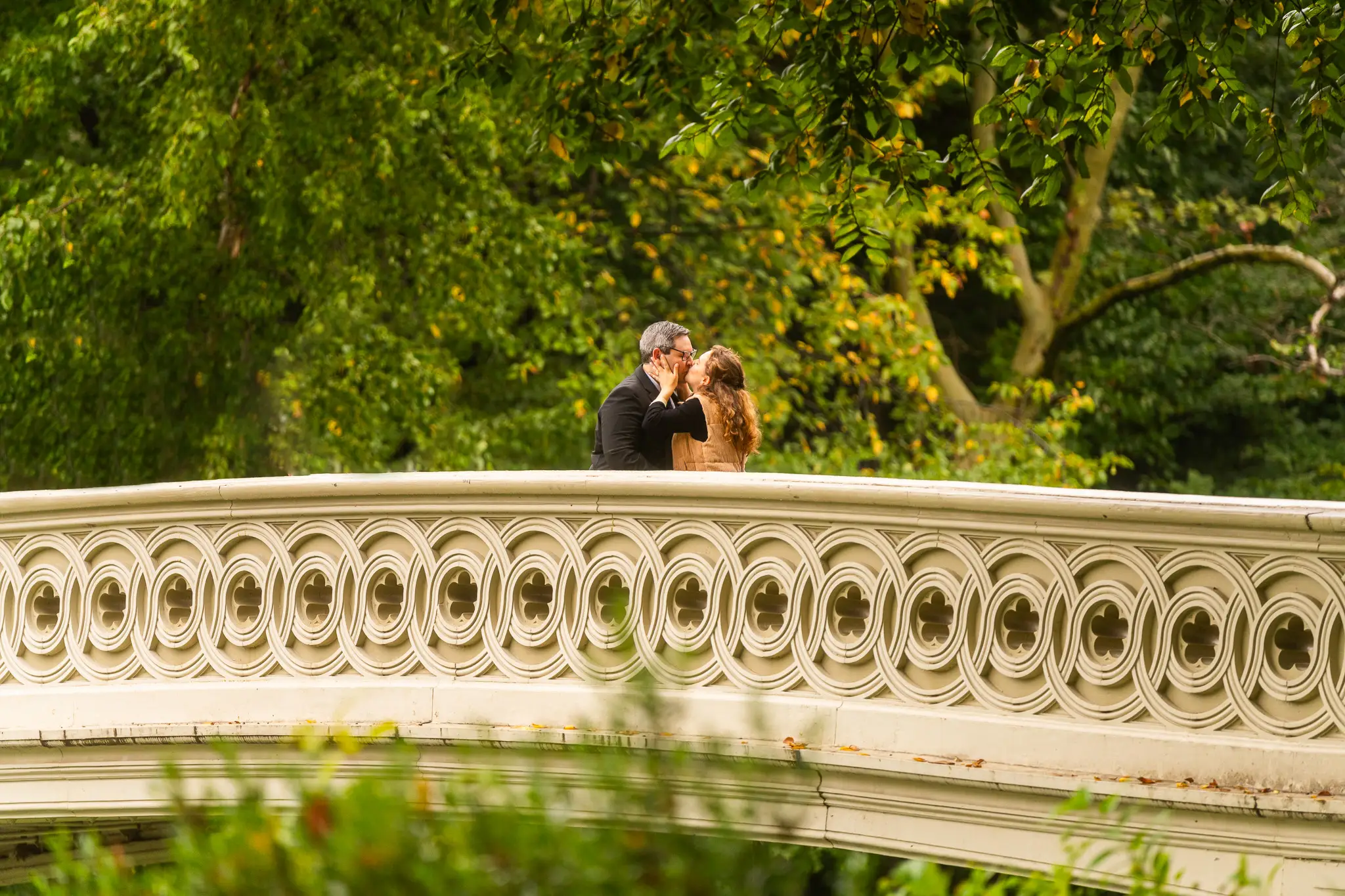 Man and woman kissing on bridge