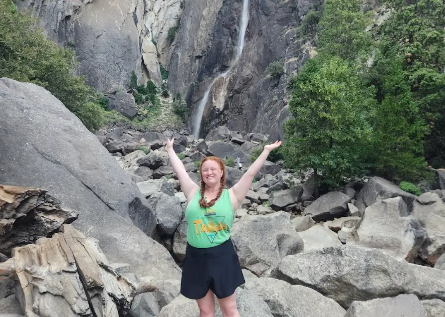The writer posing in front of a waterfall at Yosemite National Park.