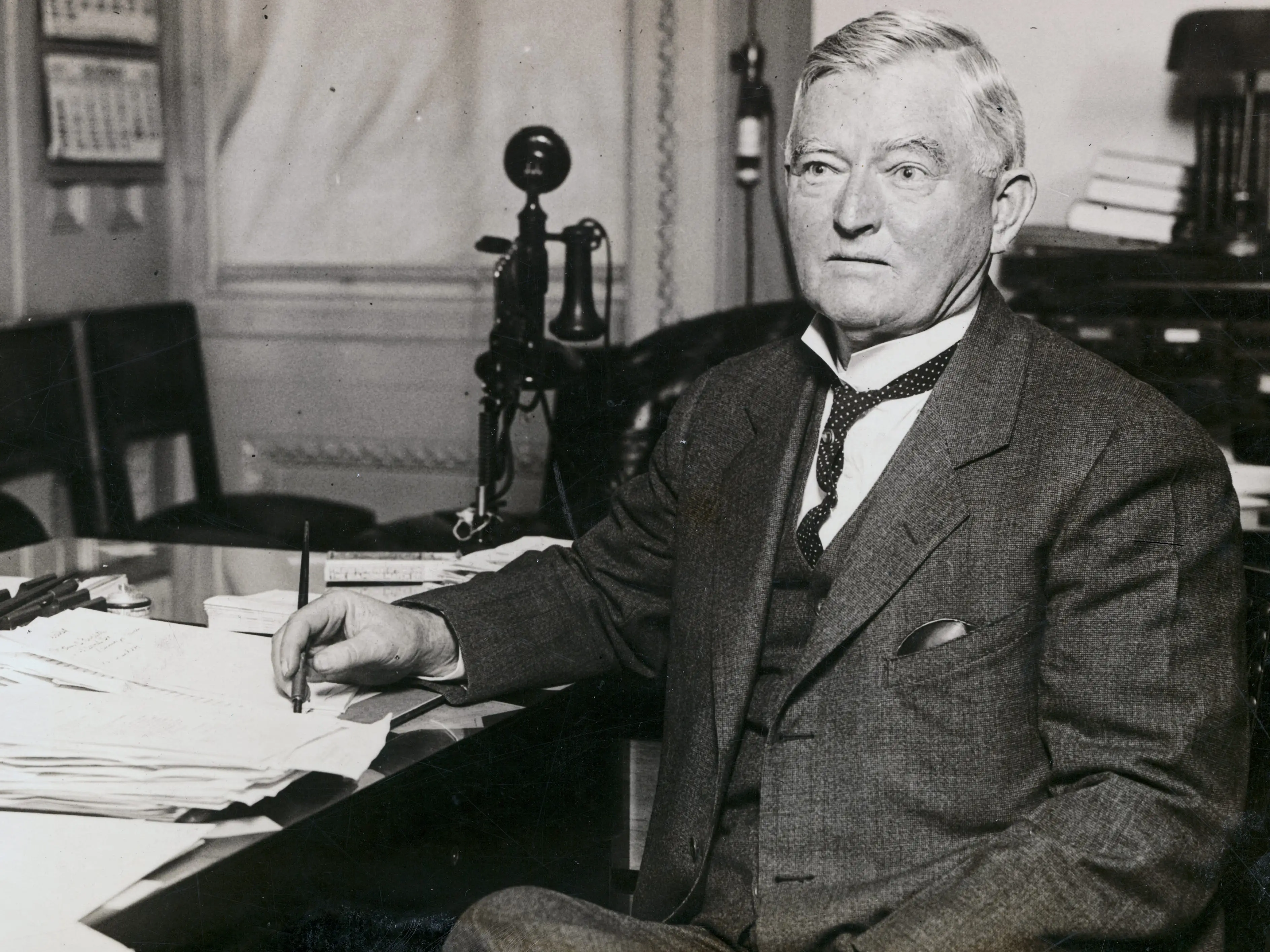 John Nance Garner sitting at a desk holding a pen.