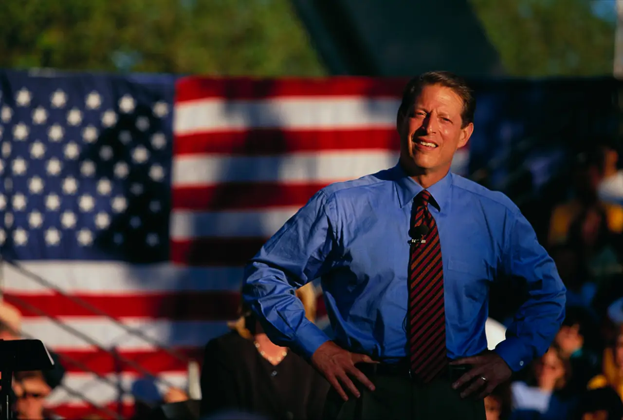 Al Gore standing in front of an American flag on the campaign trail.