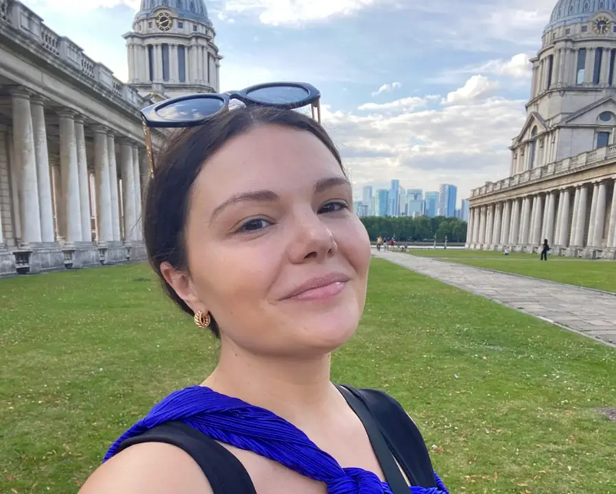 The writer standing in front of buildings in London on a sunny day.