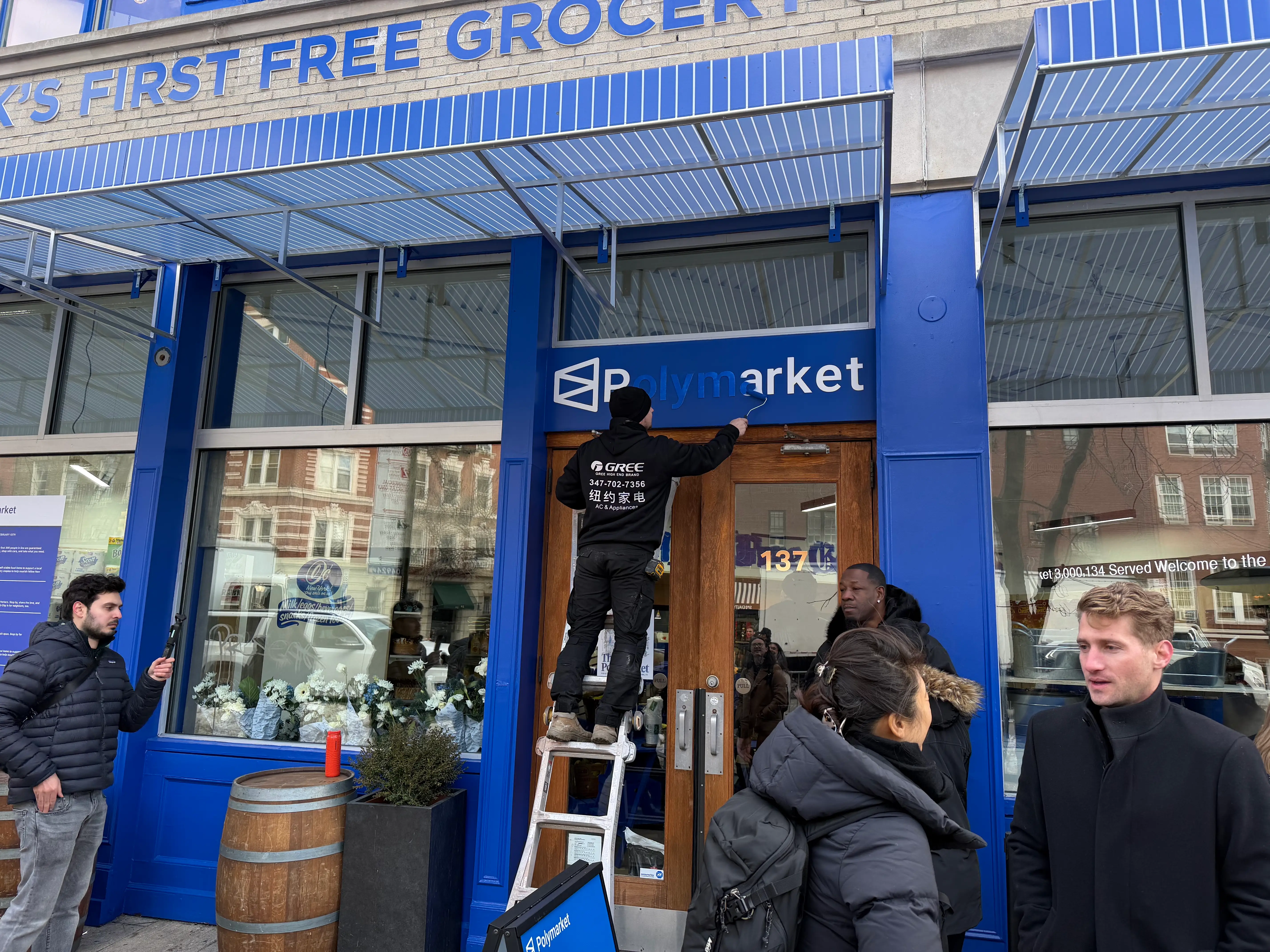A man is pictured painting over the Polymarket logo.