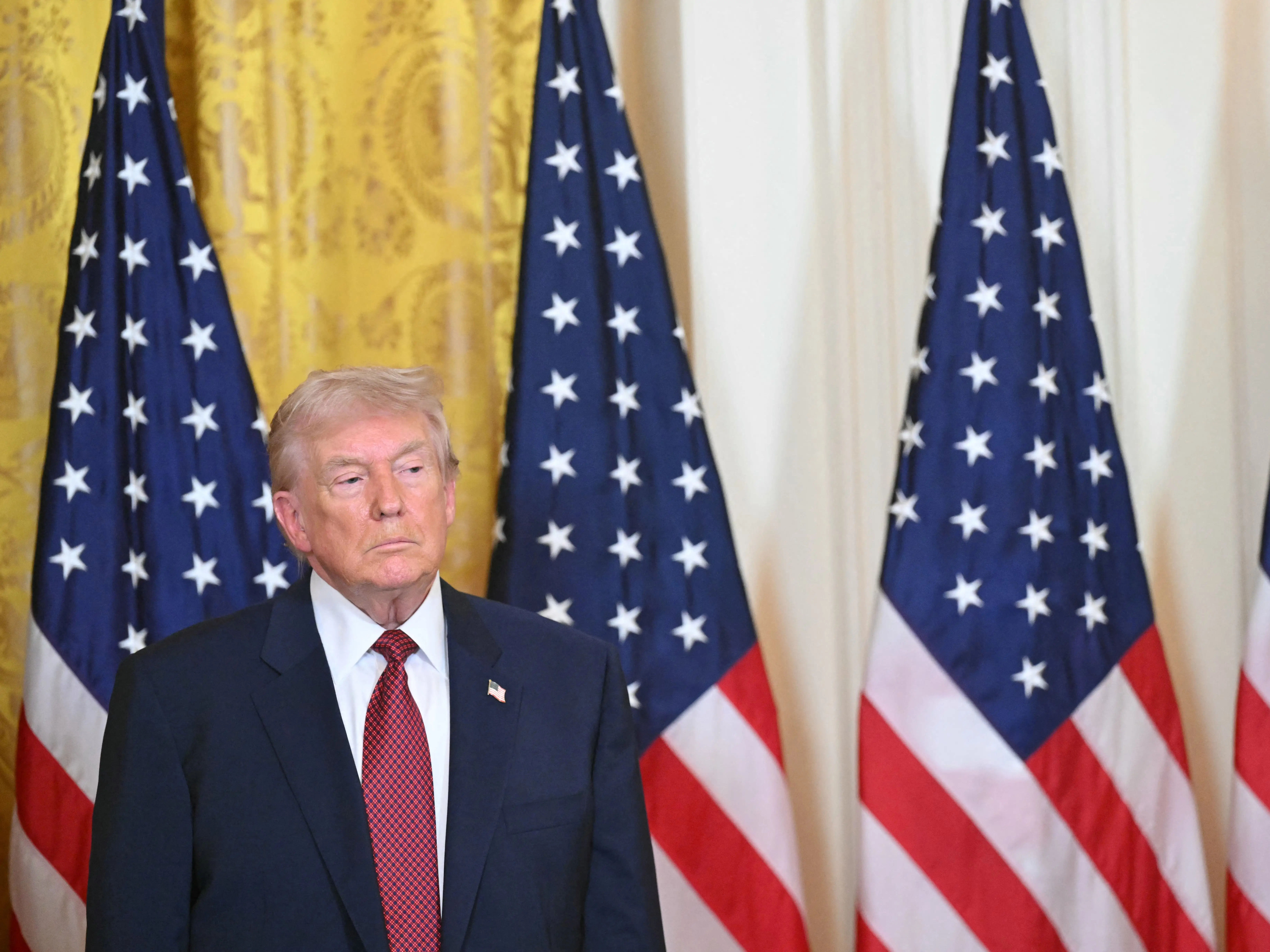 Donald Trump stands in front of American flags at the WHite House