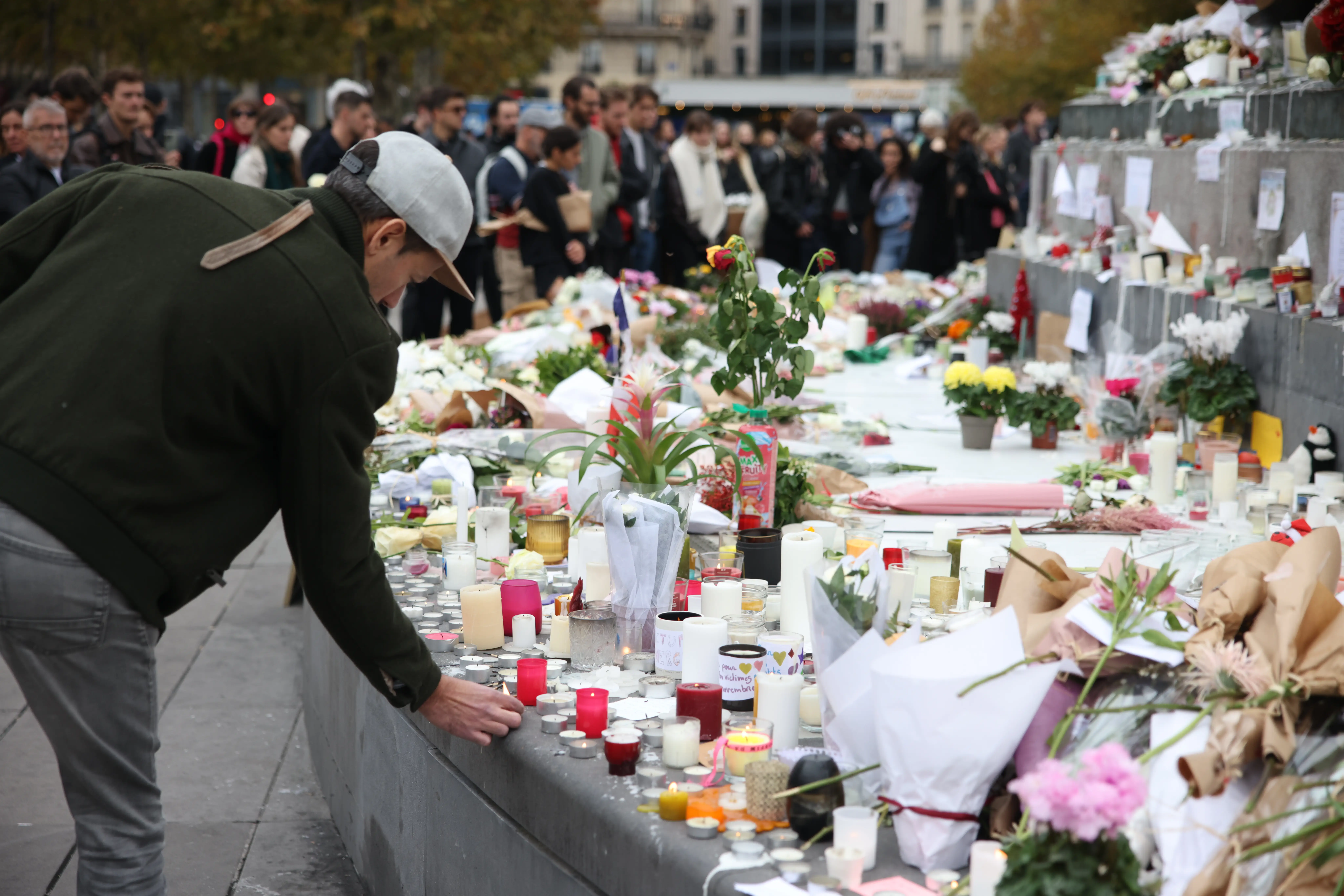 People place flowers and candles at a memorial marking 10 years since the Paris attack.