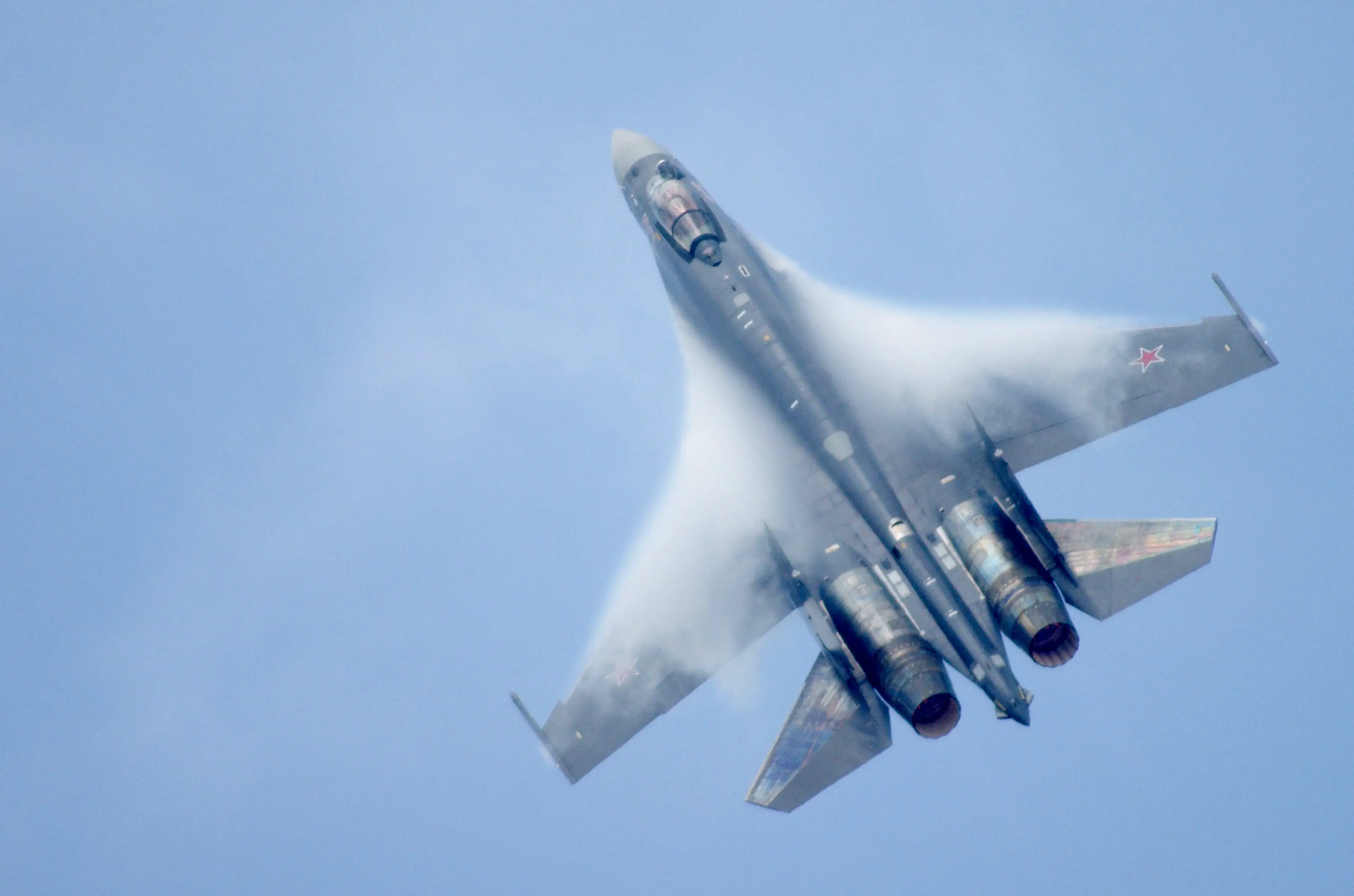 A grey fighter jet in a blue sky