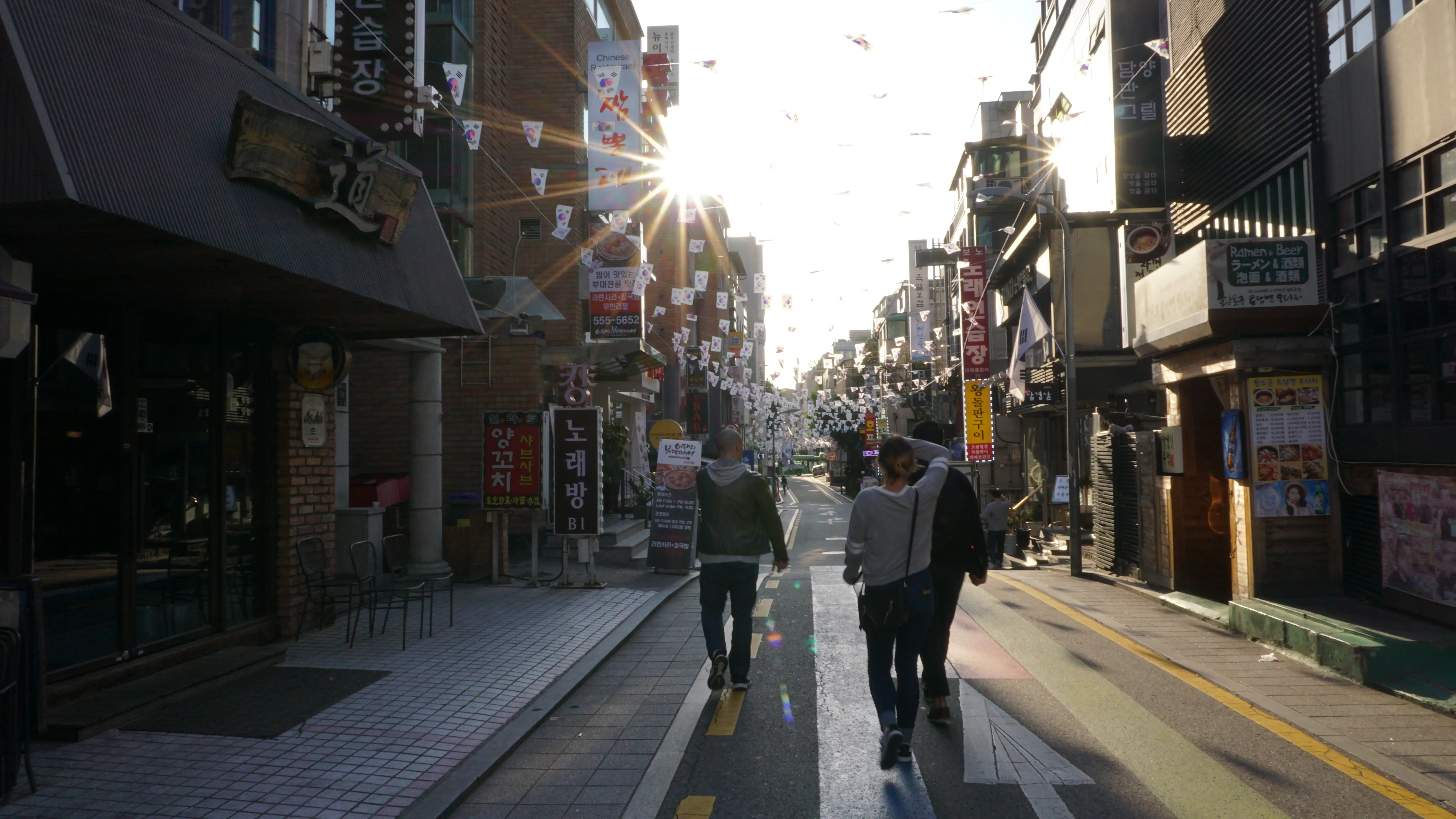 A group of friends walk down a street in Seoul, Korea.