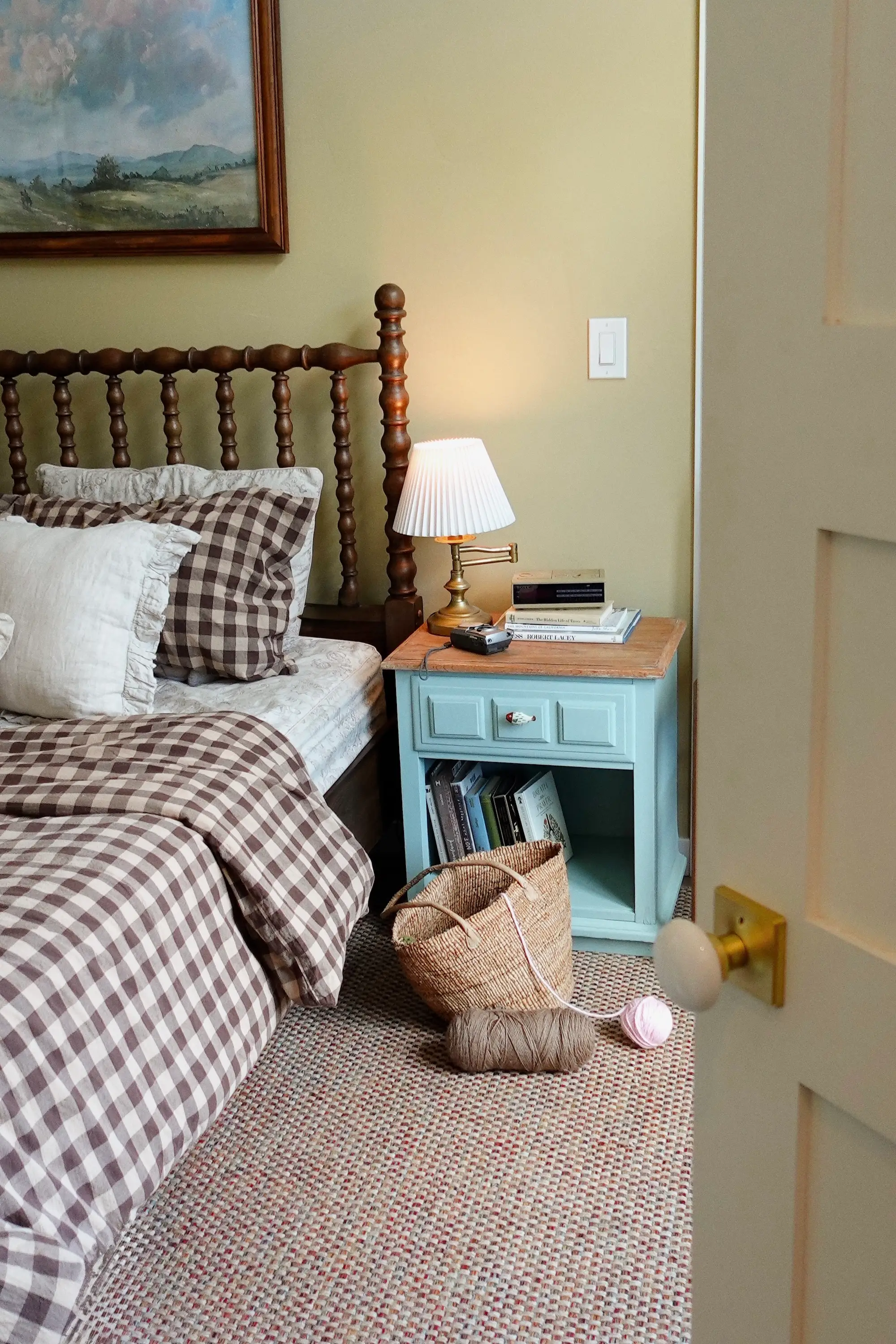 A bedroom with a nightstand and painting on the wall.