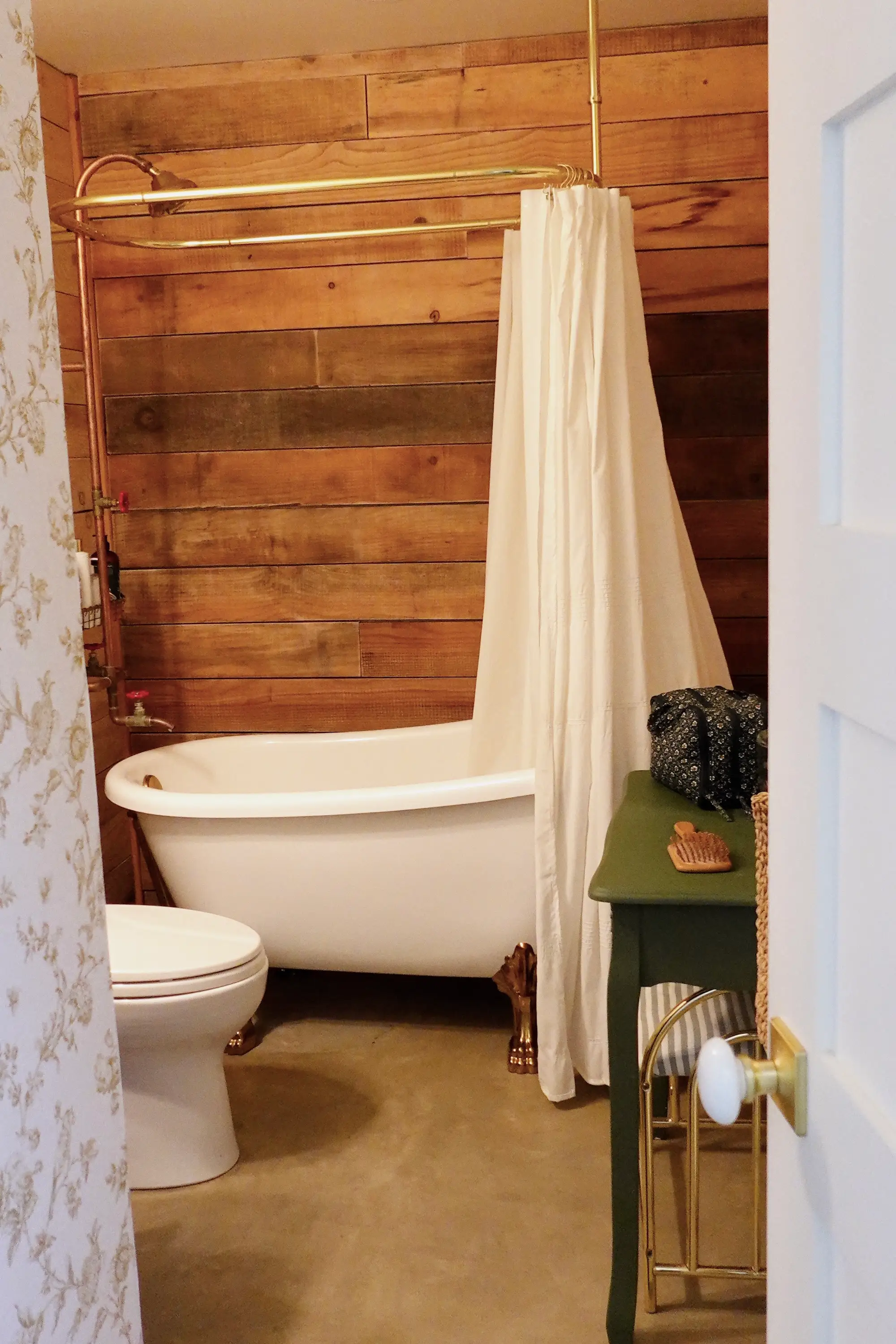 A bathroom with wooden walls and a clawfoot tub.