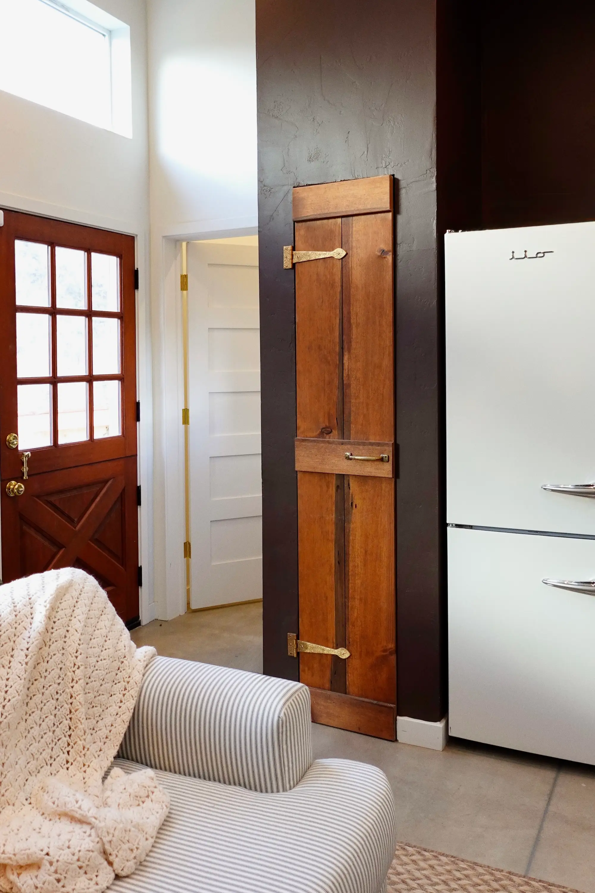 A living area with a couch, a small closet, and a red door.
