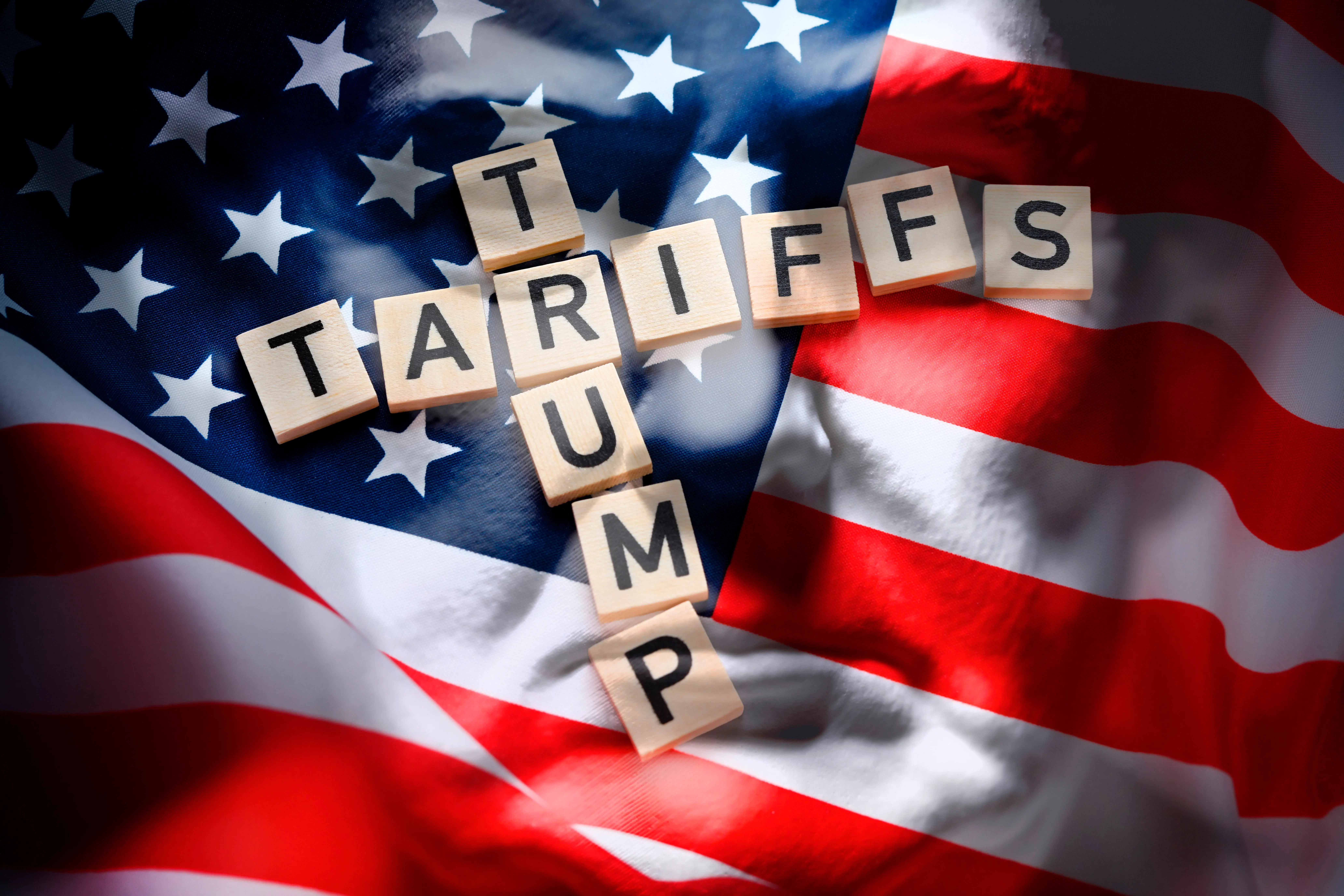 Buchstaben auf US-Fahne und Trump-Porträt bilden die Schriftzüge Trump und Tariffs, Trump-Zölle Hamburg Hamburg Deutschland ** NUR FÜR REDAKTIONELLE ZWECKE ** EDITORIAL USE ONLY *