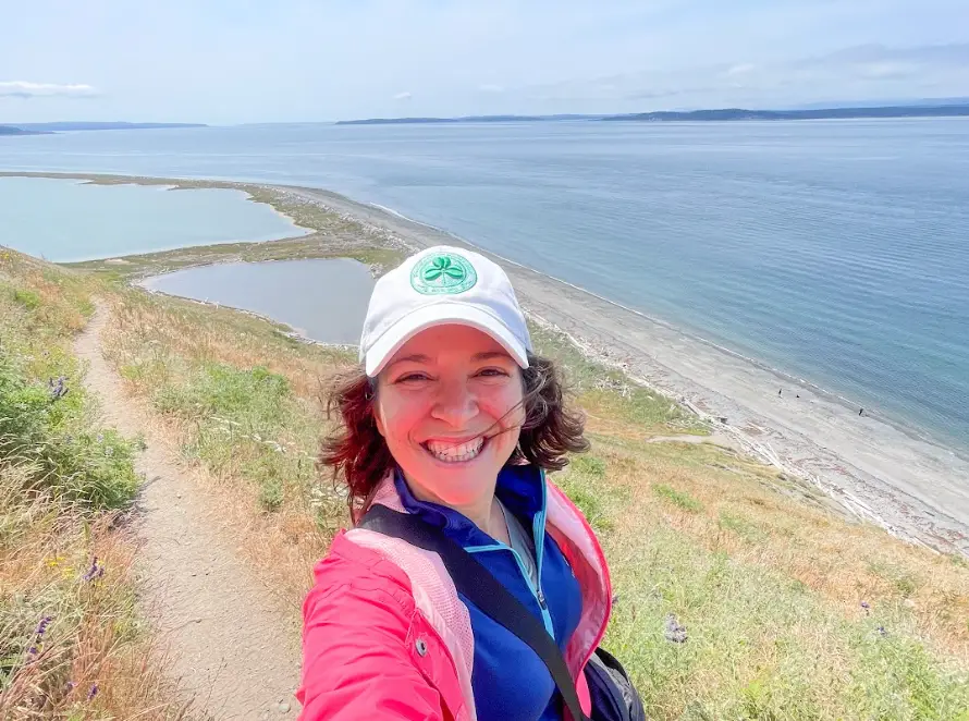 The writer going on a hike in front of the water in Washington state.