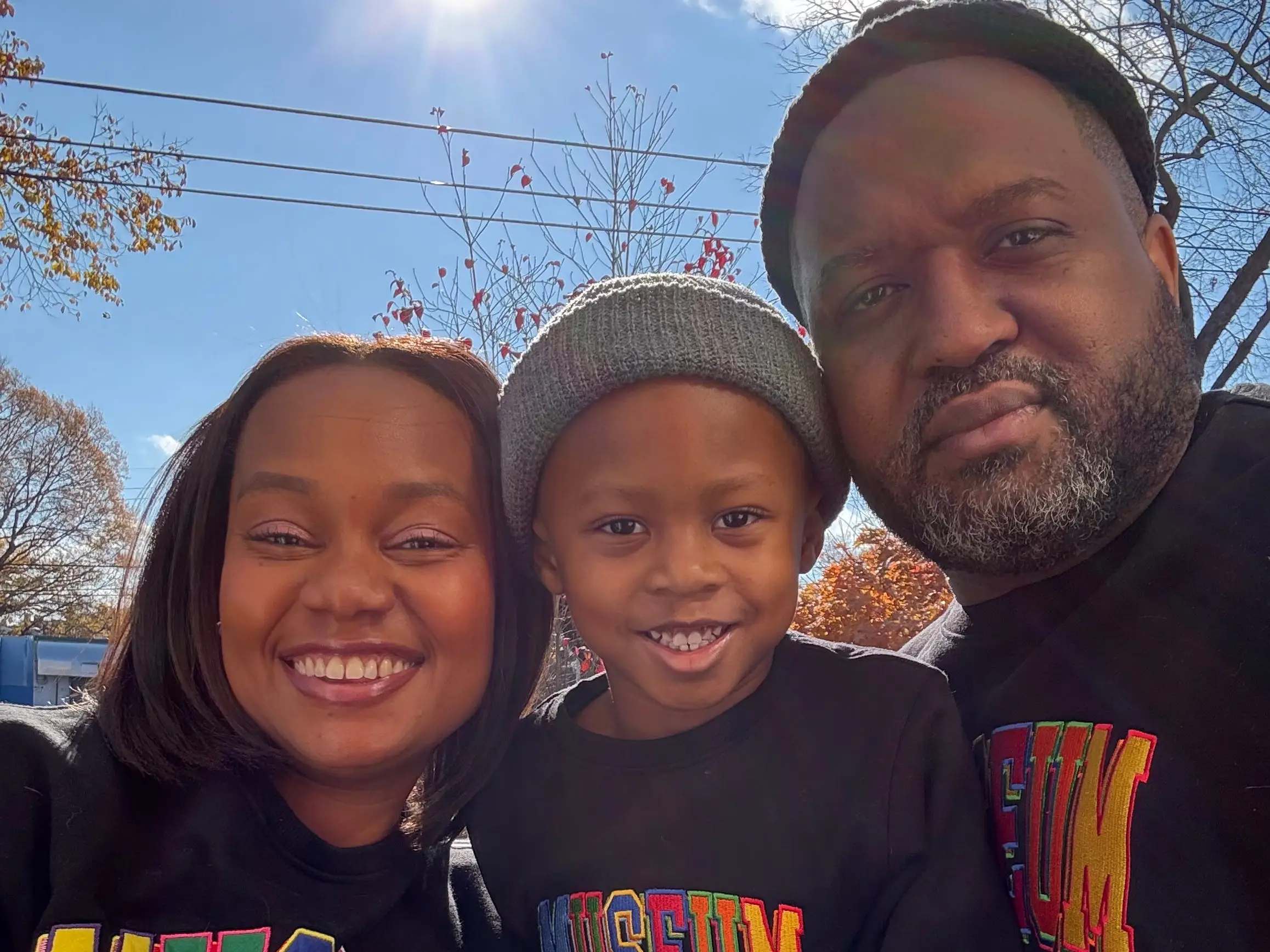 A family of three wearing matching sweatshirts.