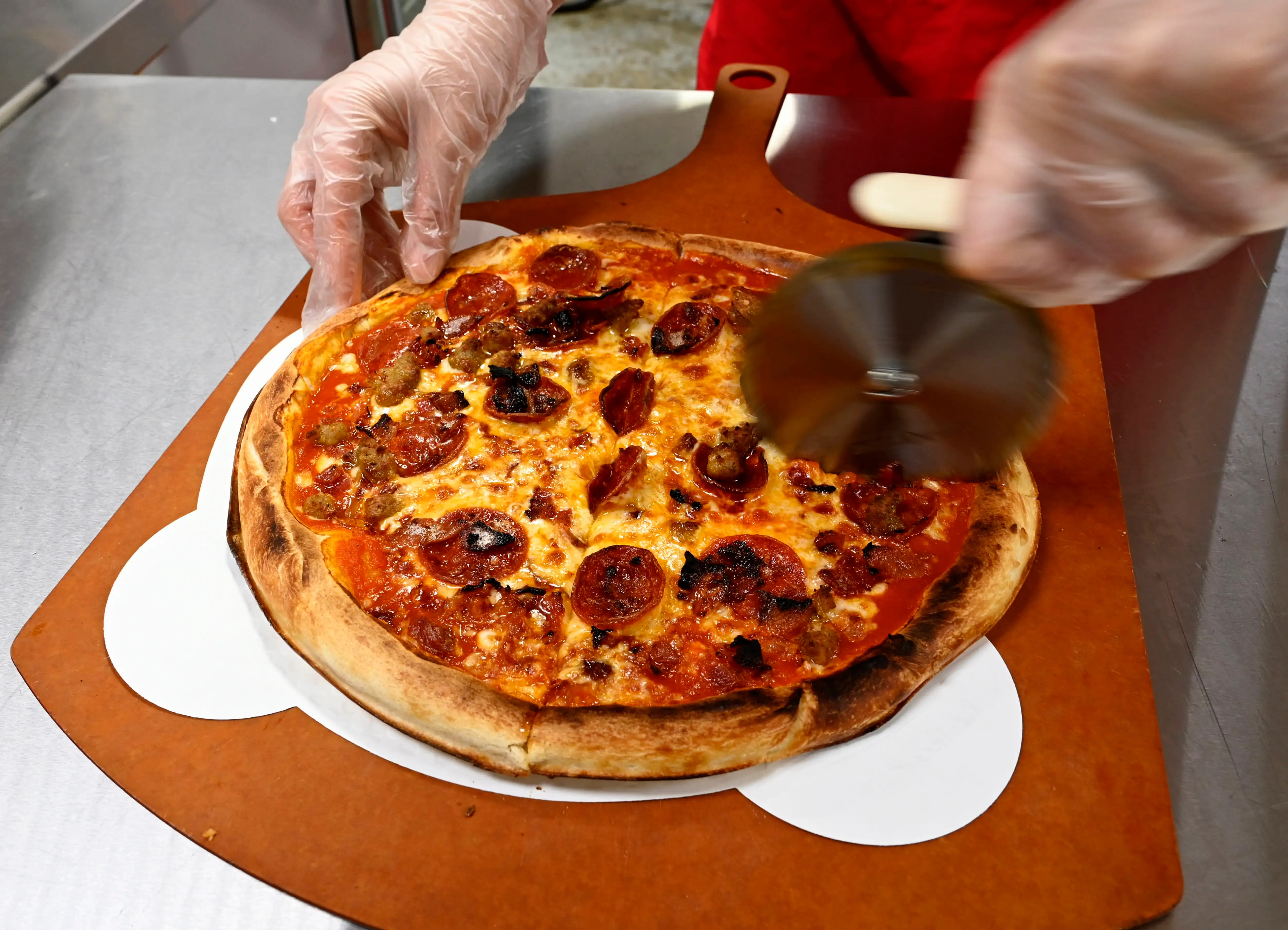A pizza cutter sliced through a pepperoni pie.