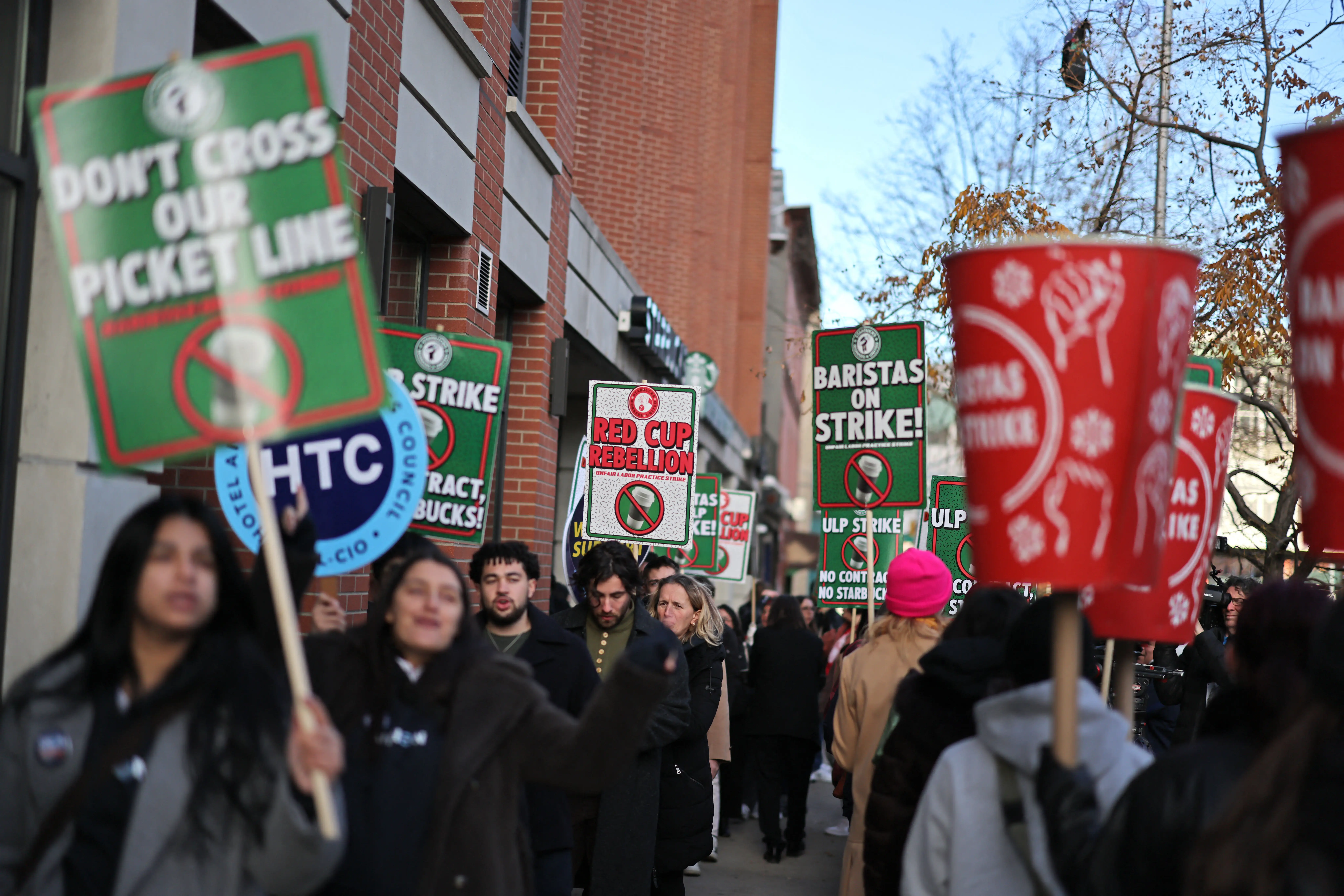 Starbucks baristas hold protest signs during a strike.