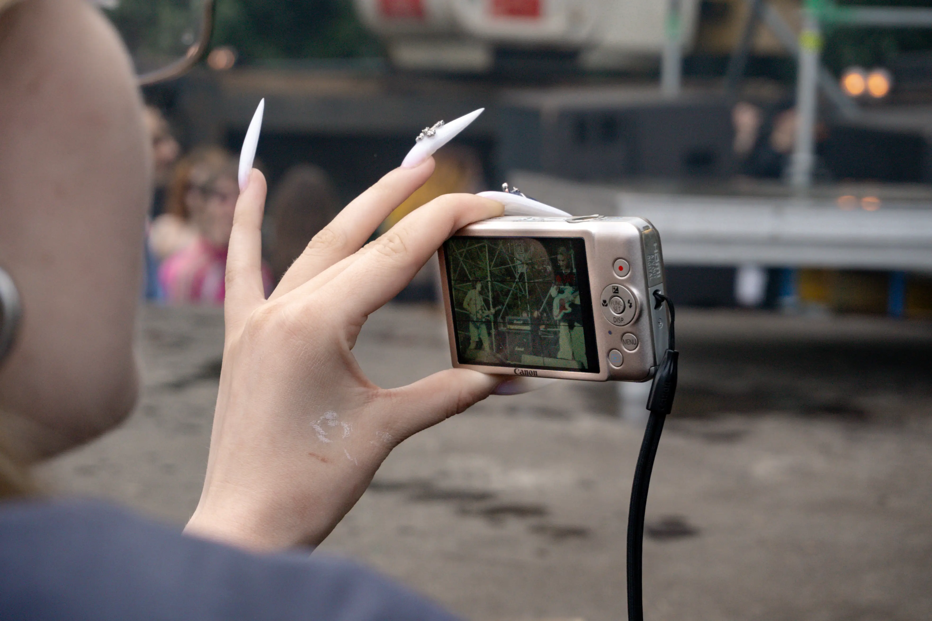 A girl films a performance on a digital compact camera.