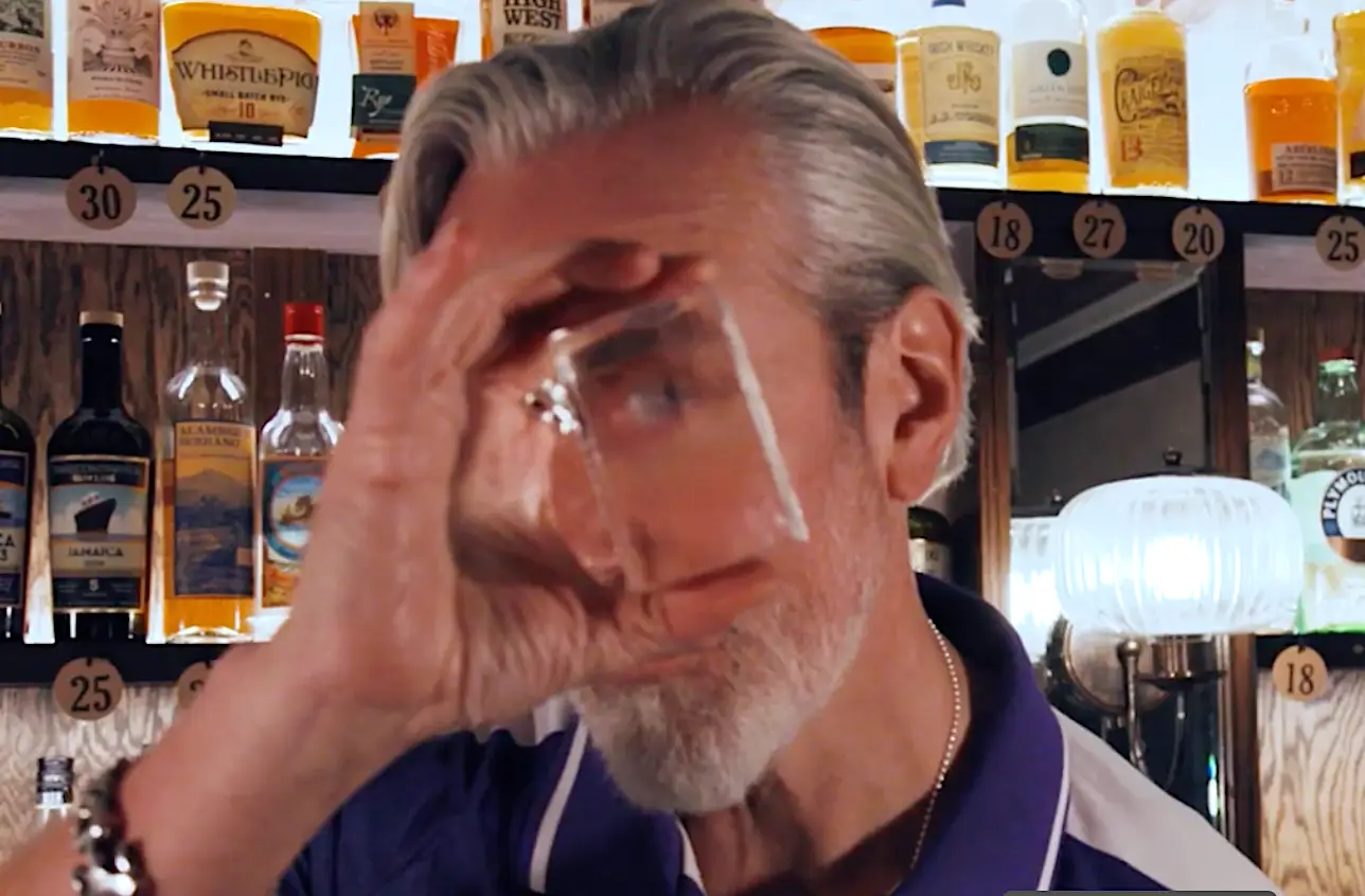 Man holding up large, crystal-clear ice cube in front of his face.