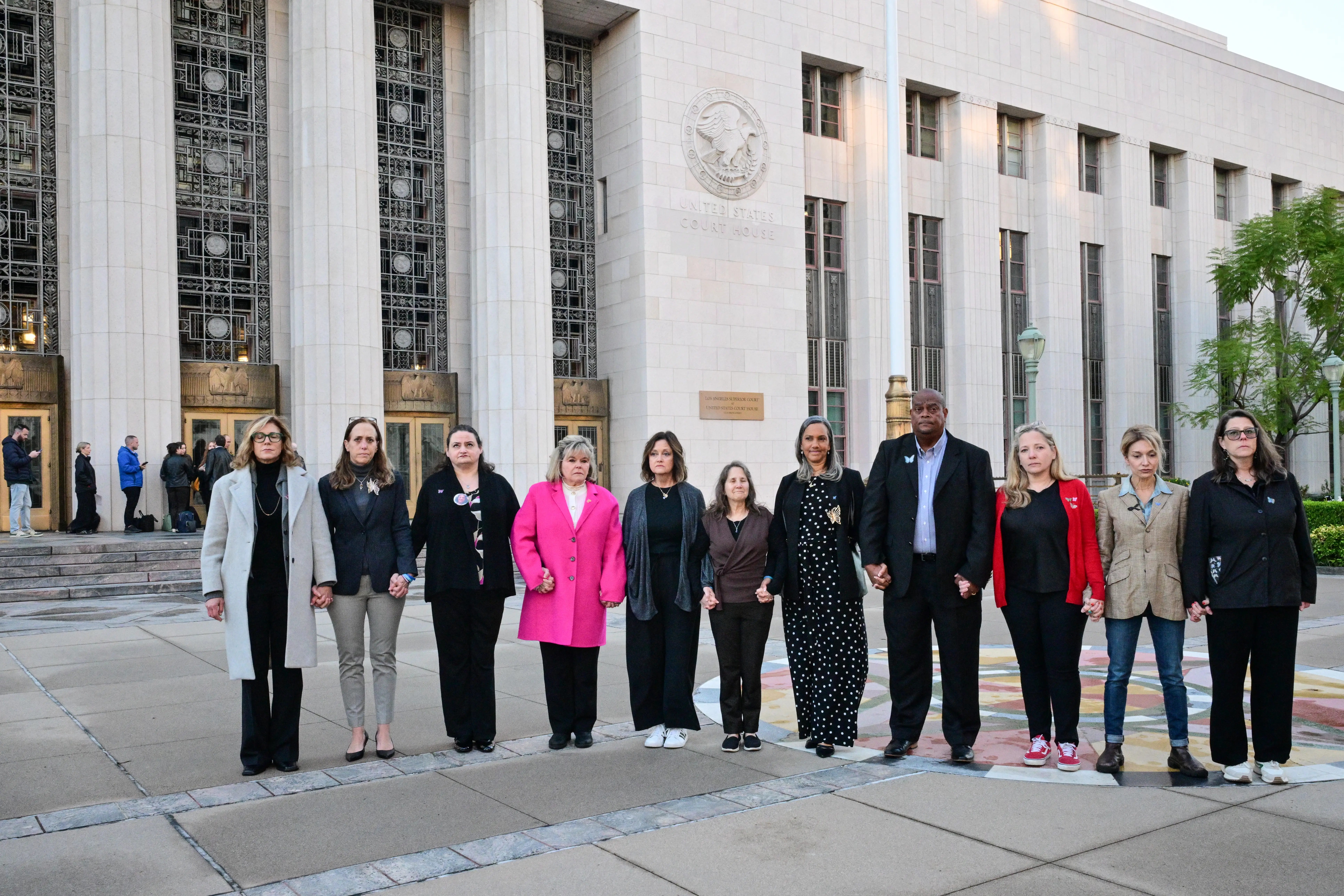 Parents and family members, including some plaintiffs in the case, hold hands as they pose together before entering the Los Angeles Superior Court for the social media trial tasked to determine whether social media giants deliberately designed their platforms to be addictive to children, in Los Angeles, on February 18, 2026. Meta CEO and Chairman Mark Zuckerberg is scheduled to testify Wednesday. (Photo by Frederic J. Brown / AFP via Getty Images)