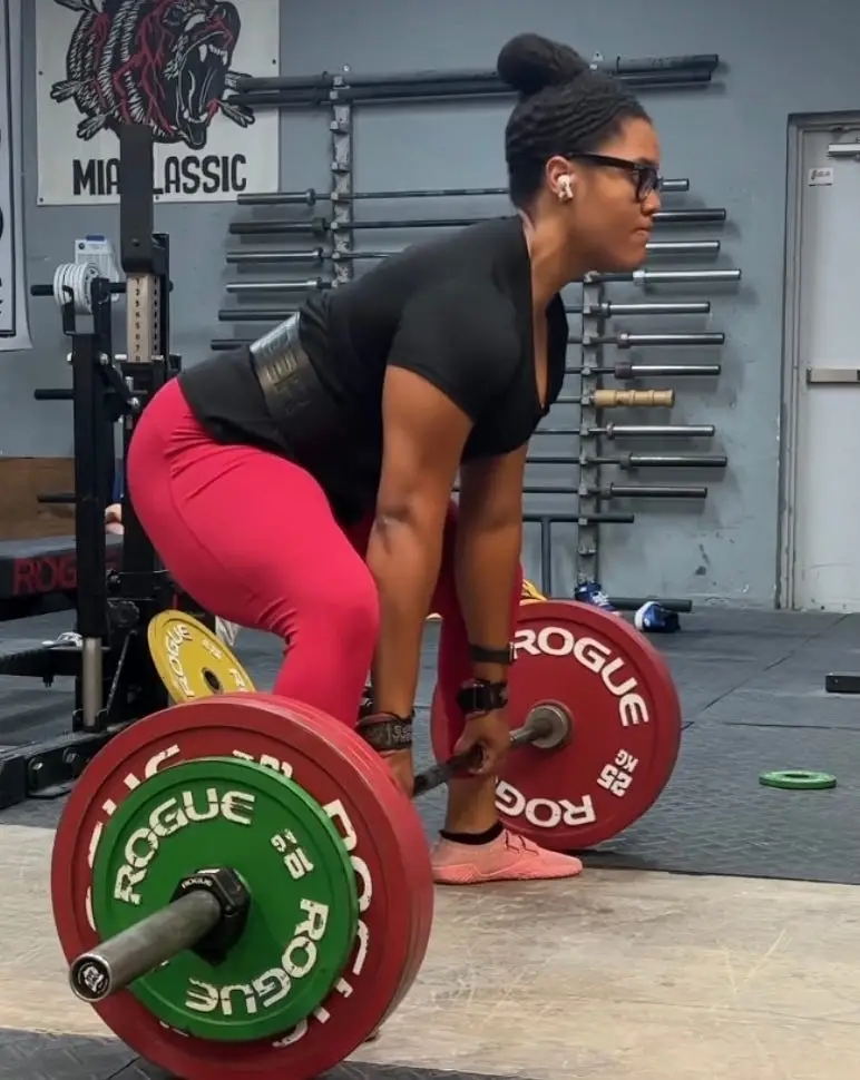 A woman deadlifting a heavy barbell.