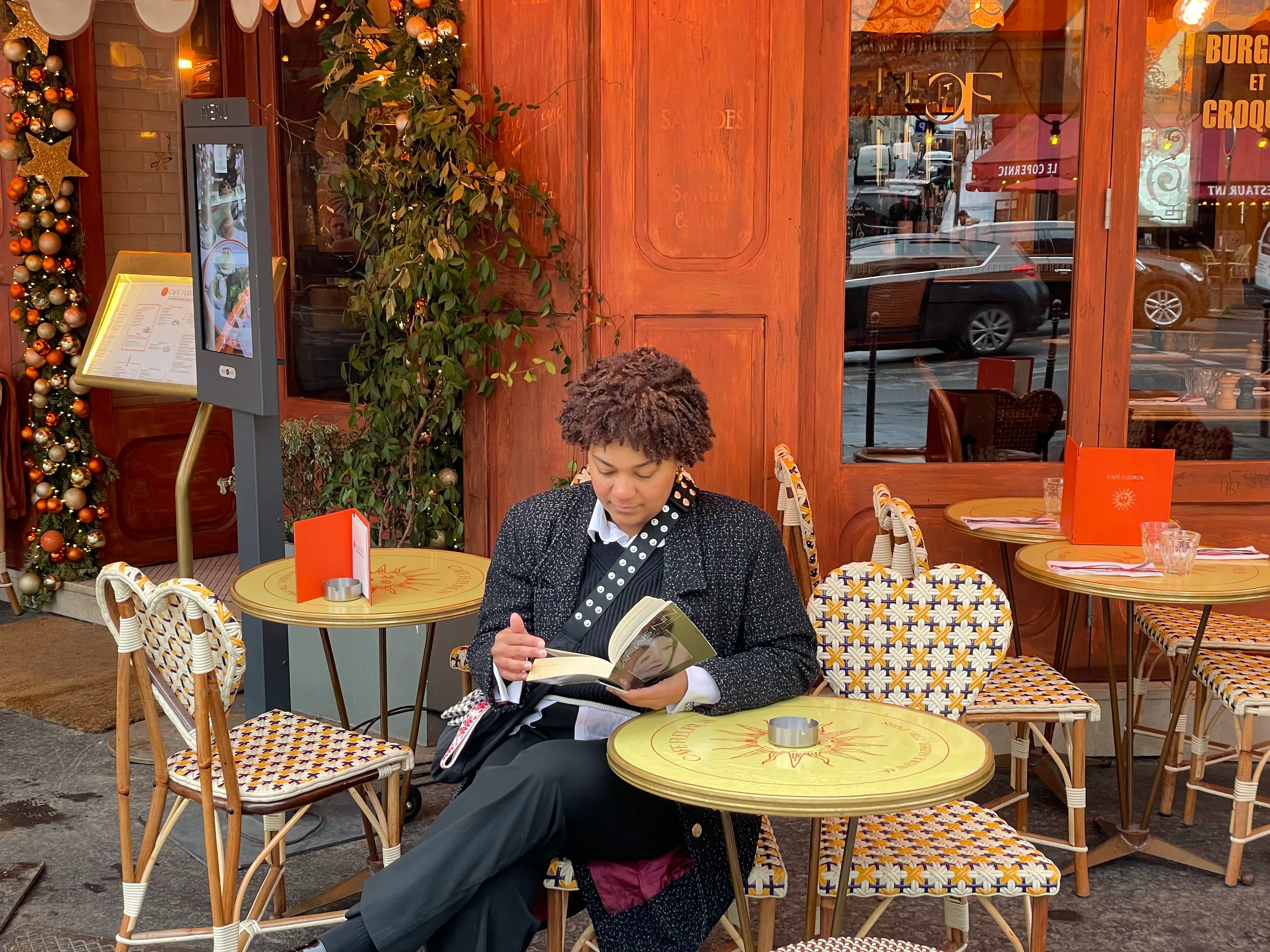 Woman reading book outside at cafe in PAris