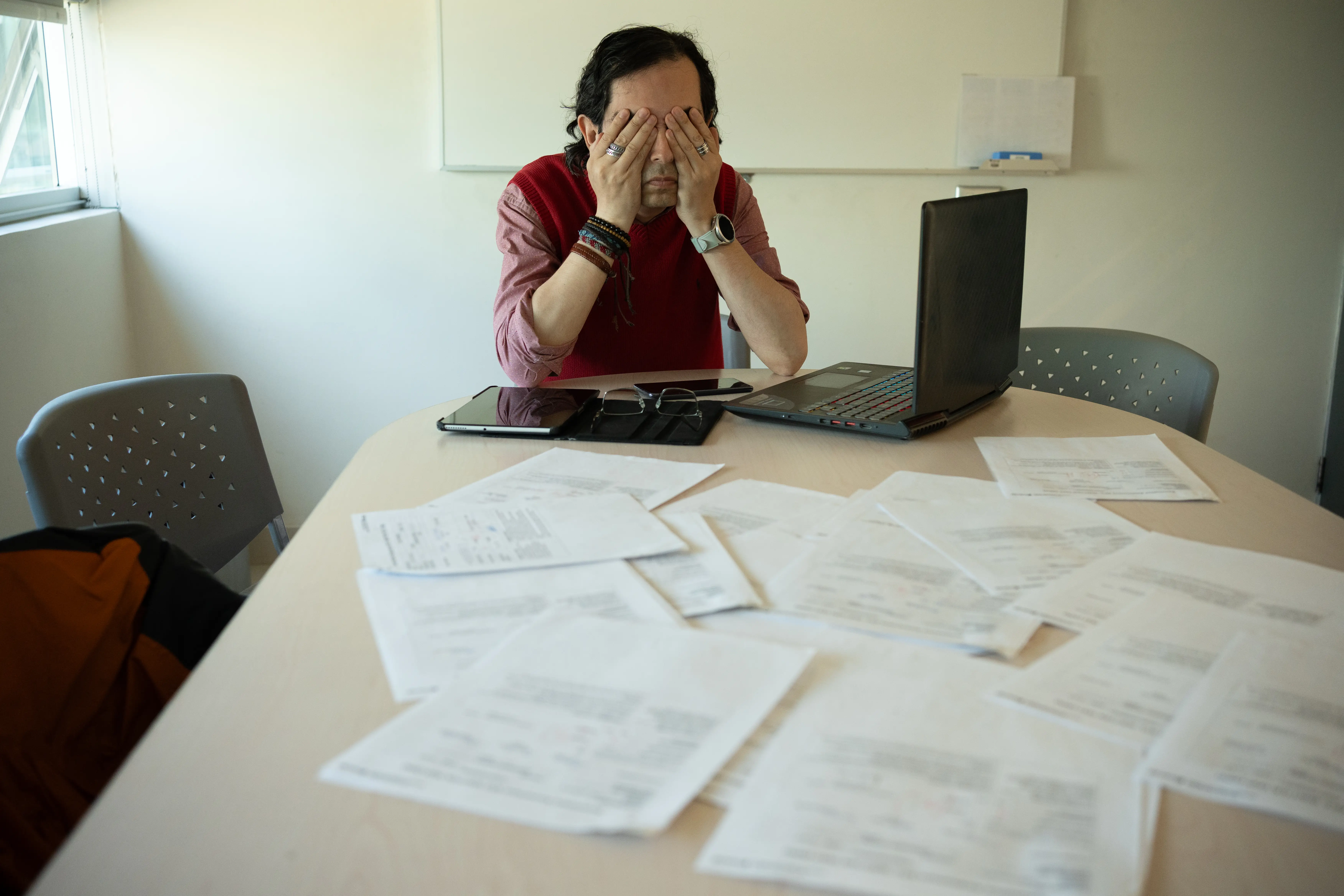 a man sitting at a desk surrouned by papers and laptop