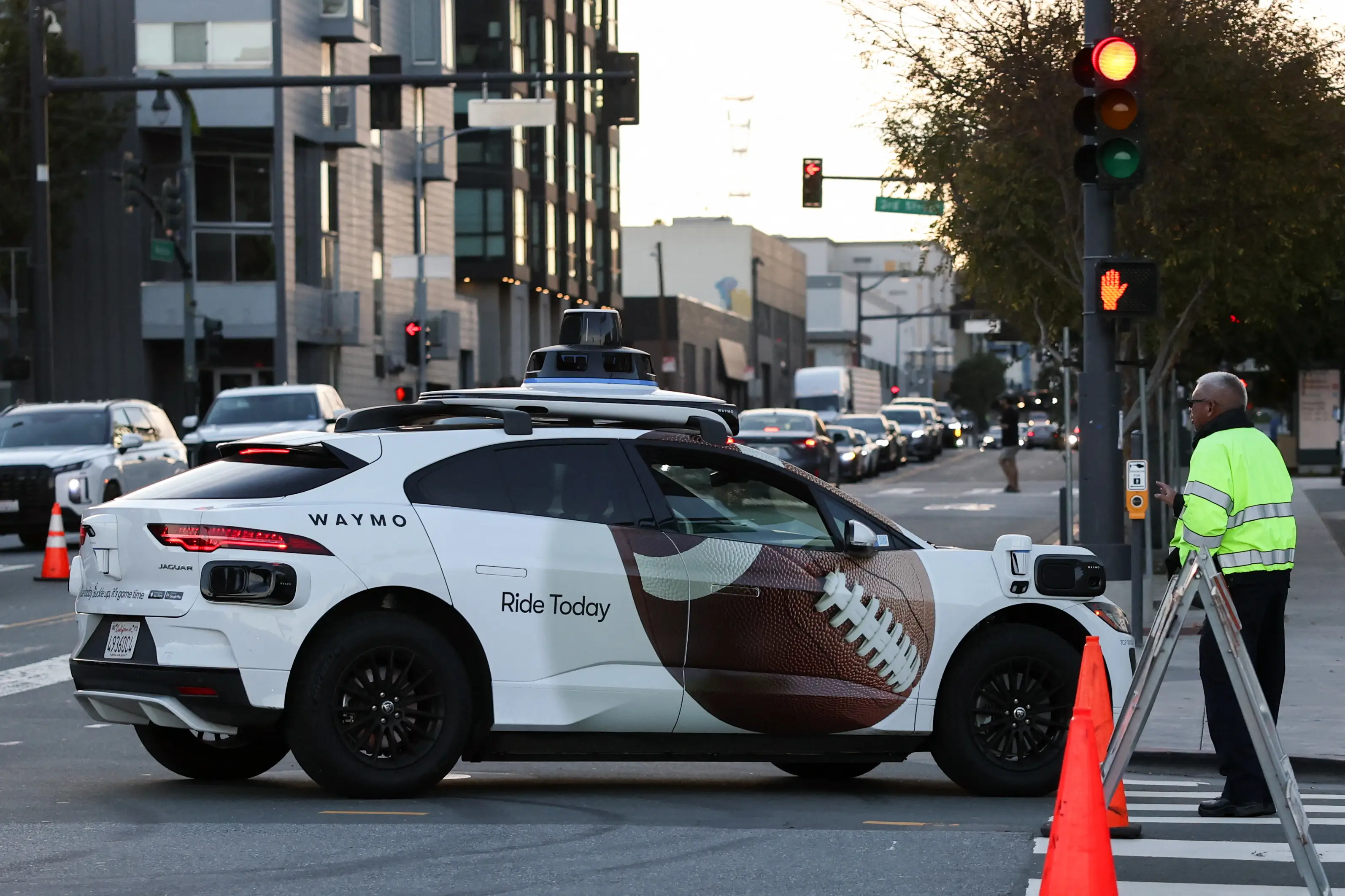 A Waymo autonomous self-driving Jaguar electric vehicle wrapped with a football graphic is seen navigating a roadblock during NFL Super Bowl weekend in San Francisco, California on February 7, 2026. (Photo by Patrick T. Fallon / AFP via Getty Images)