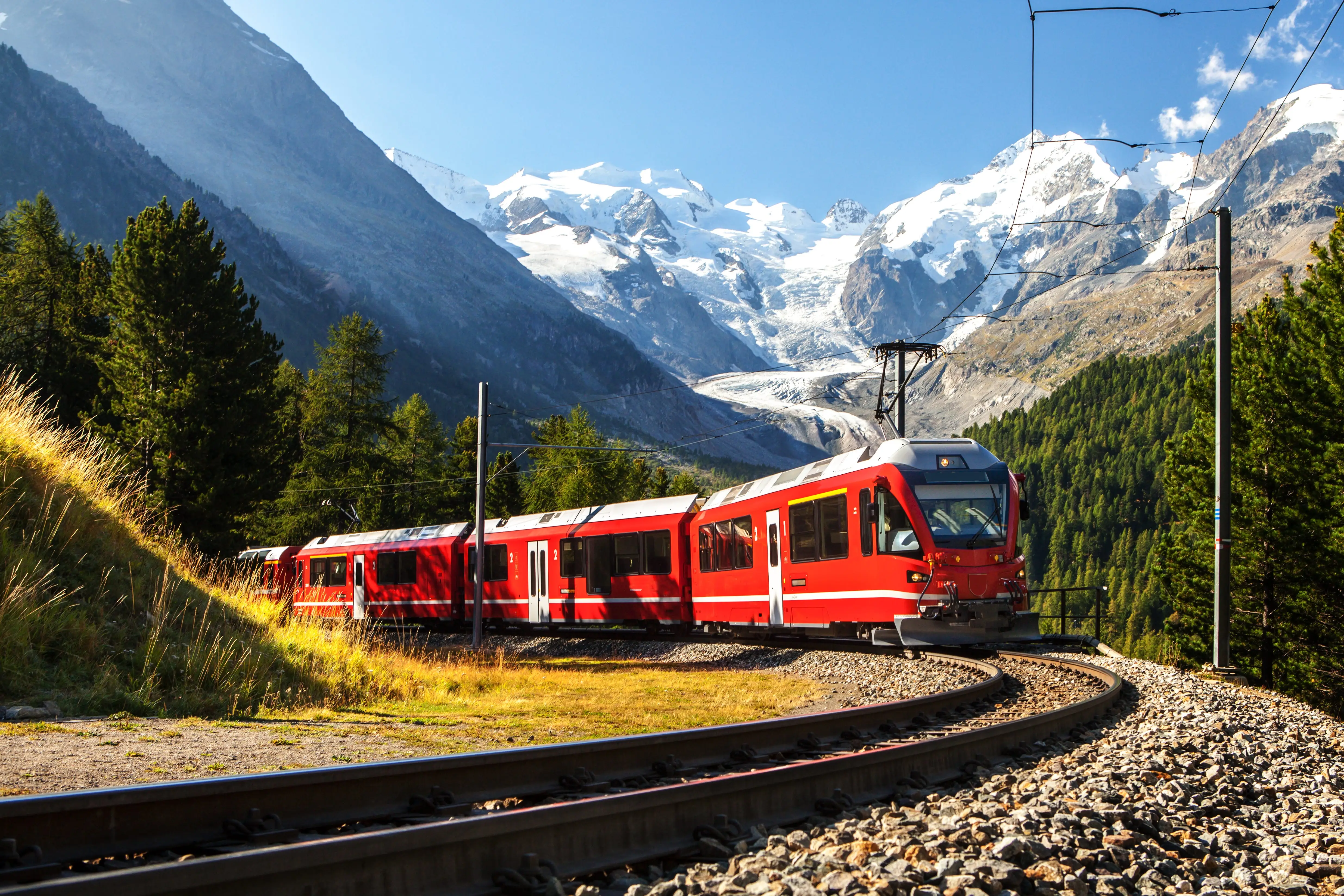 Train by trees, mountains