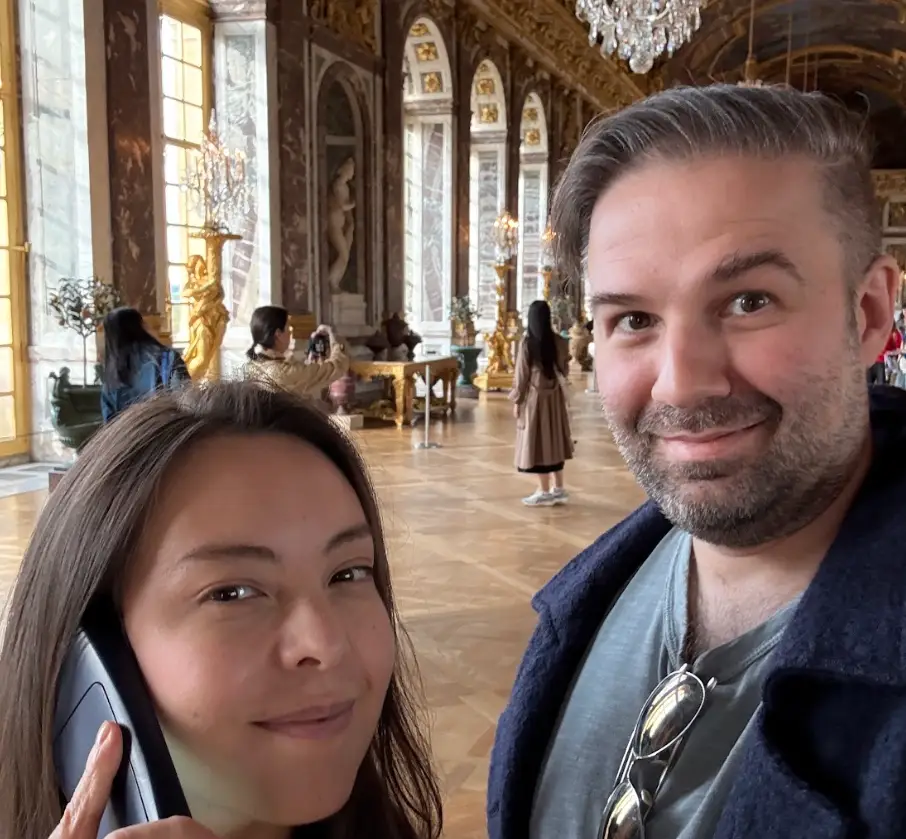 The writer and his wife standing indoors in Versailles, Paris.