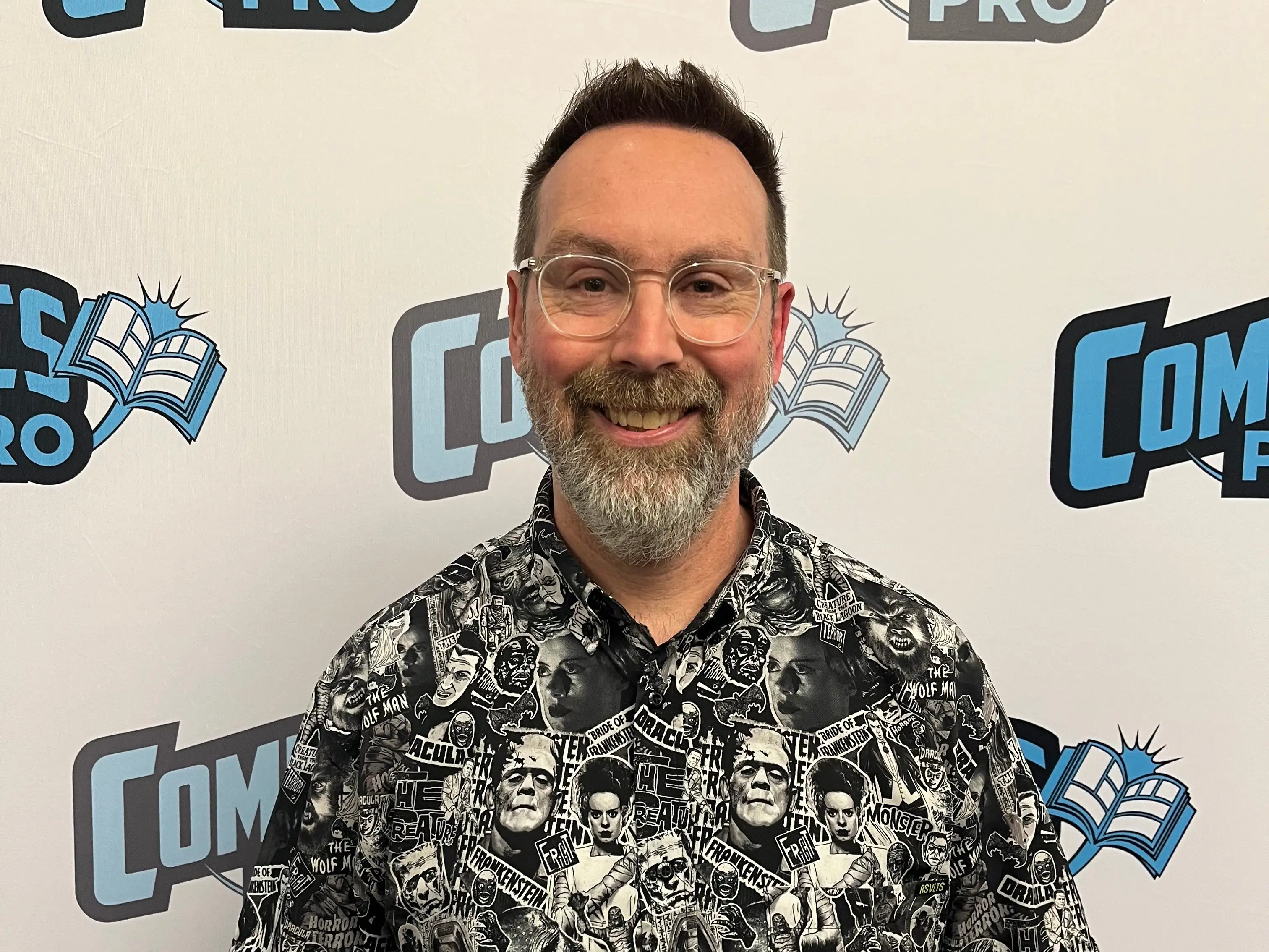Marc Bowker in a button up shirt covered with images of Frankenstein and other classic monsters.