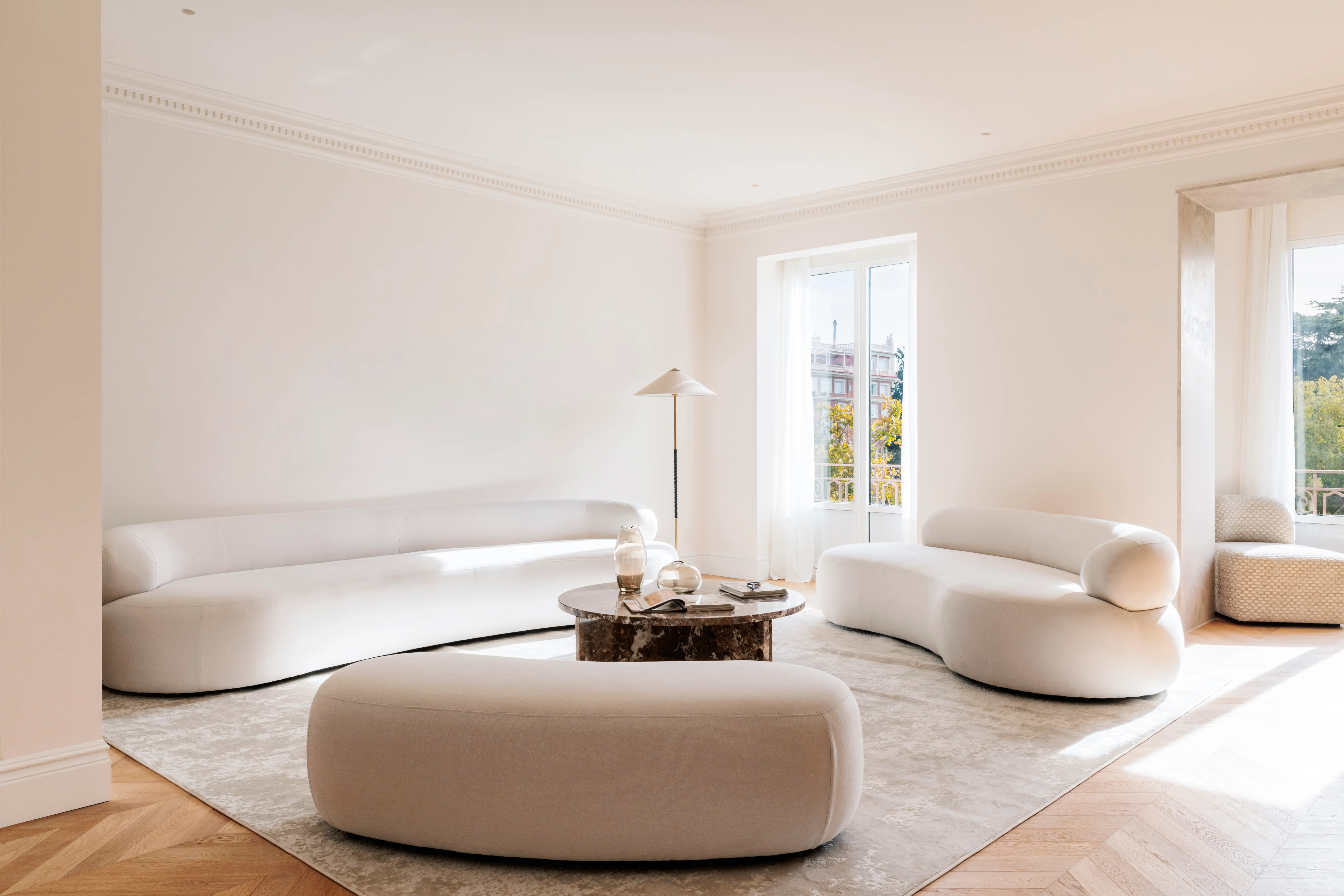 Living room with white, light gray carpet and curved furniture