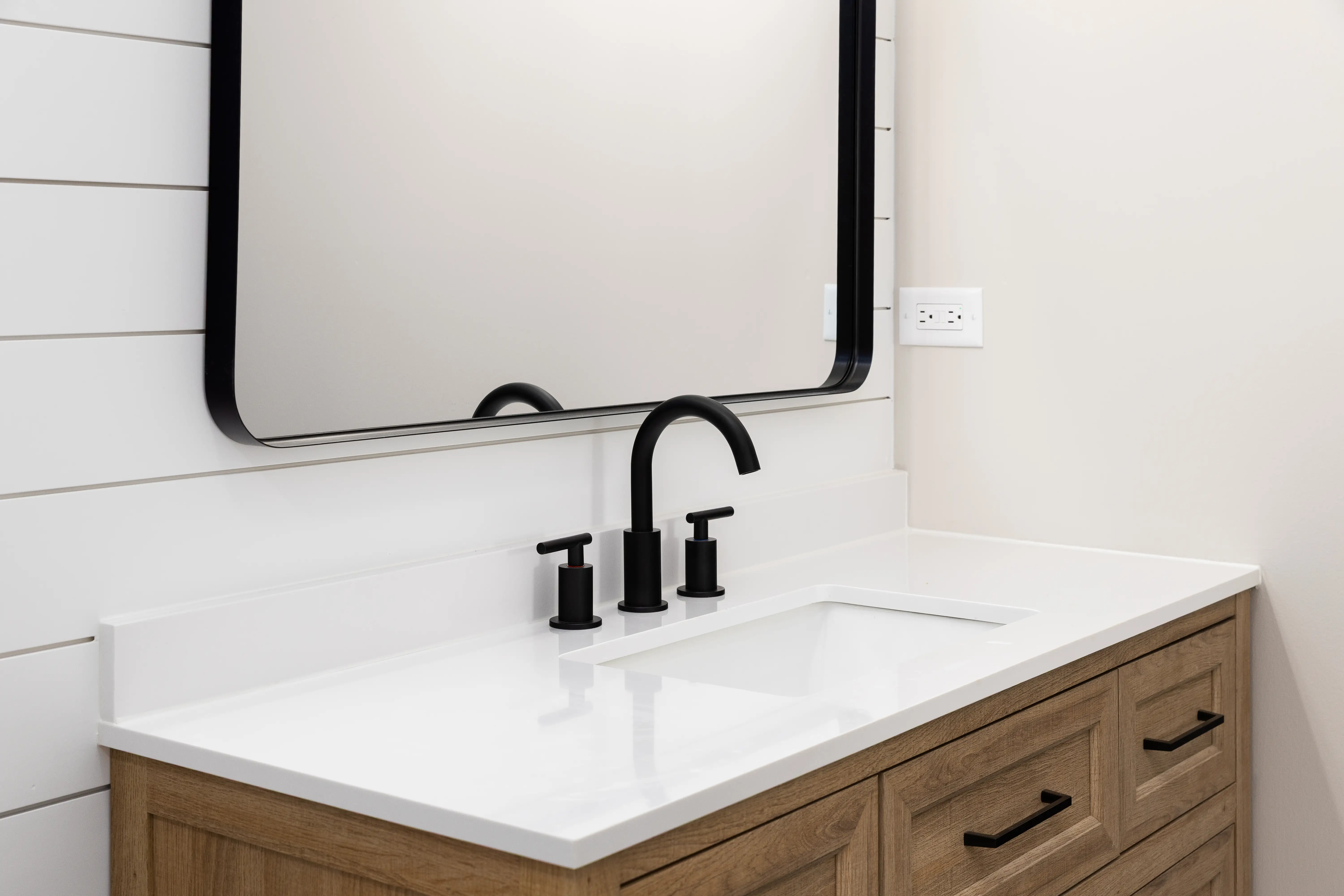Sink with black hardware, shiplap behind it