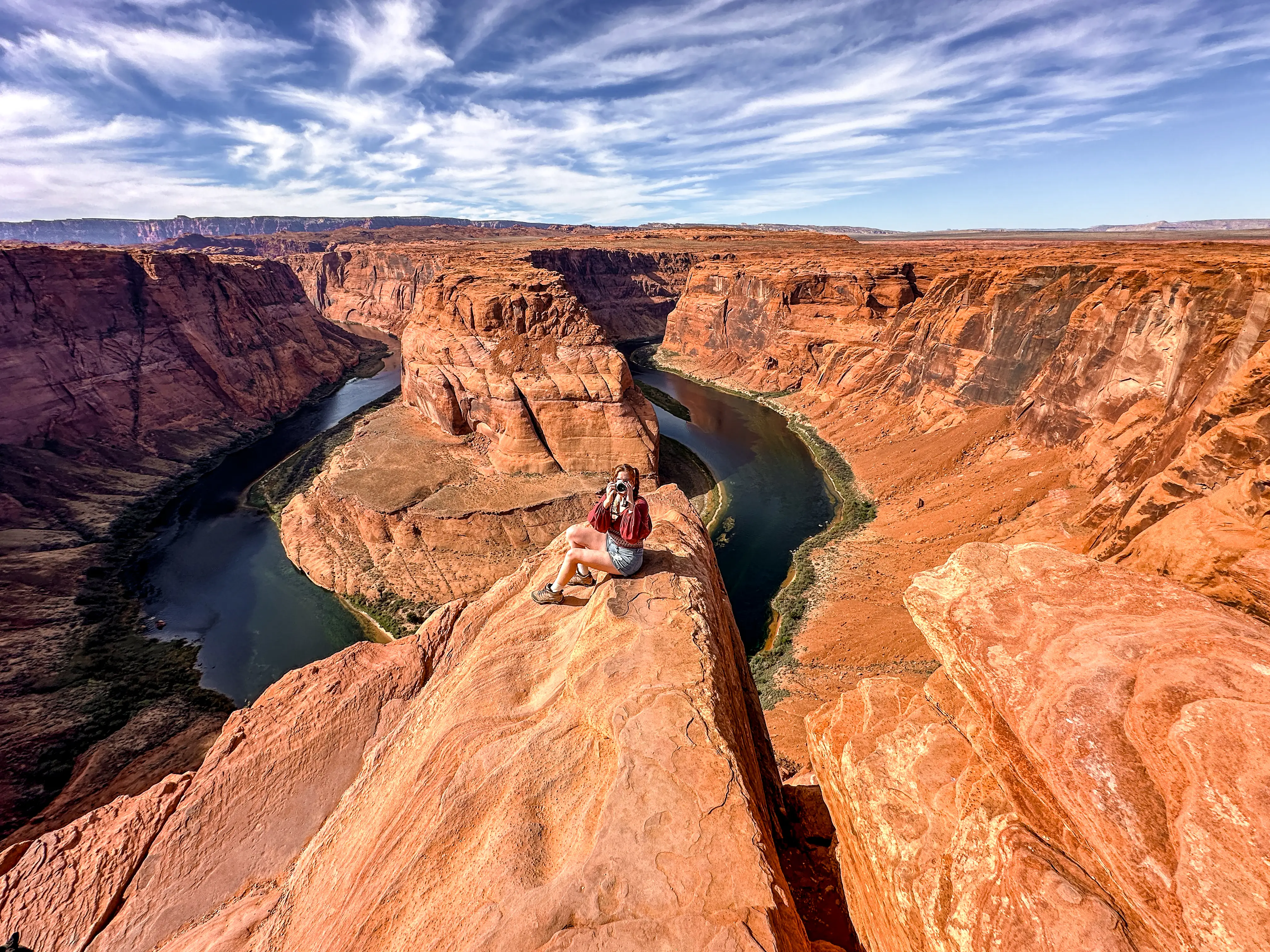 Alexandra sits on a red-rock canyon with a camera.